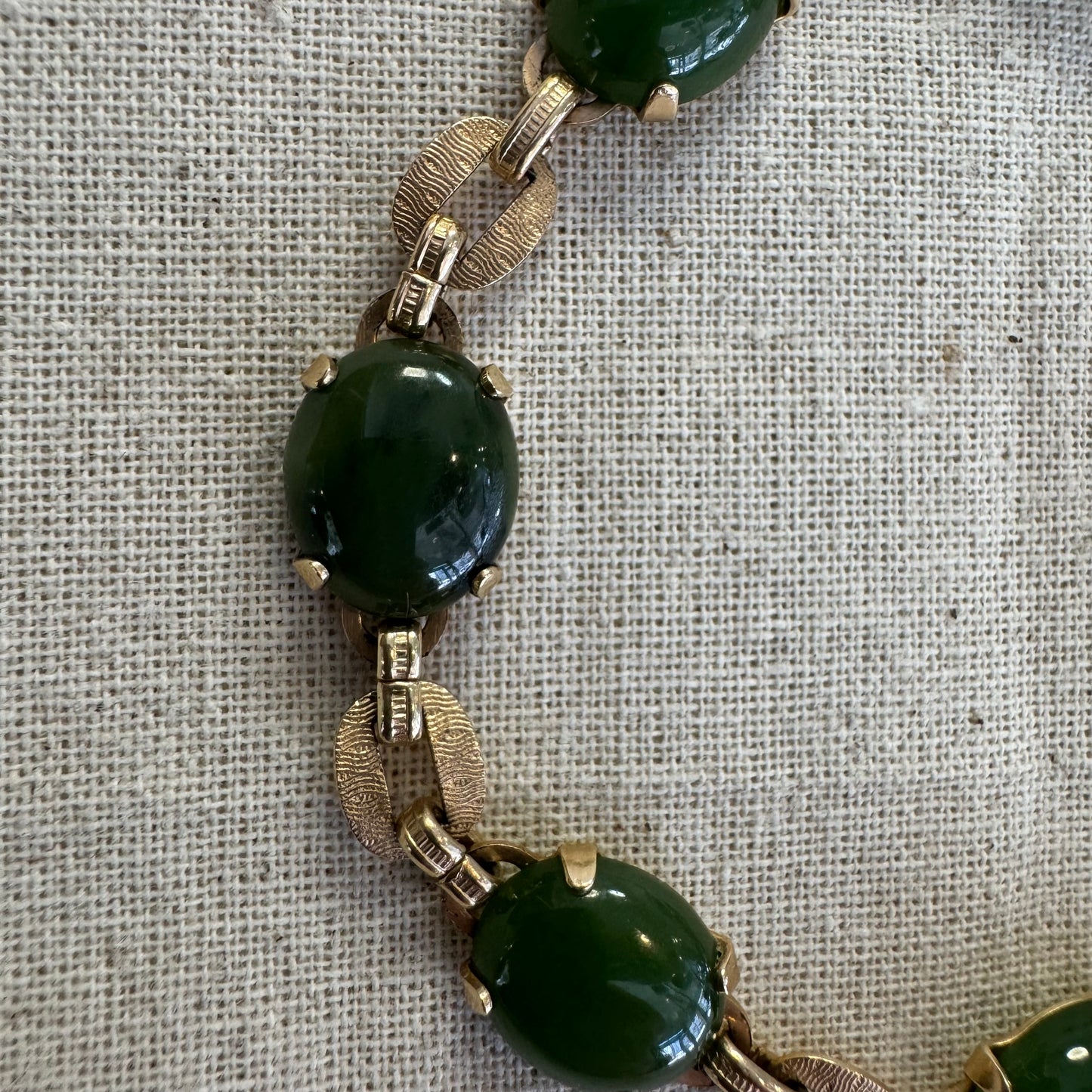 צמיד זהב צהוב 14 קראט משובץ באבני ג’ייד ירוקות בחיתוך קבושון (cabochon) בעיצוב אליפטי, המחוברות ביניהן בחוליות זהב עם טקסטורה מעניינת.