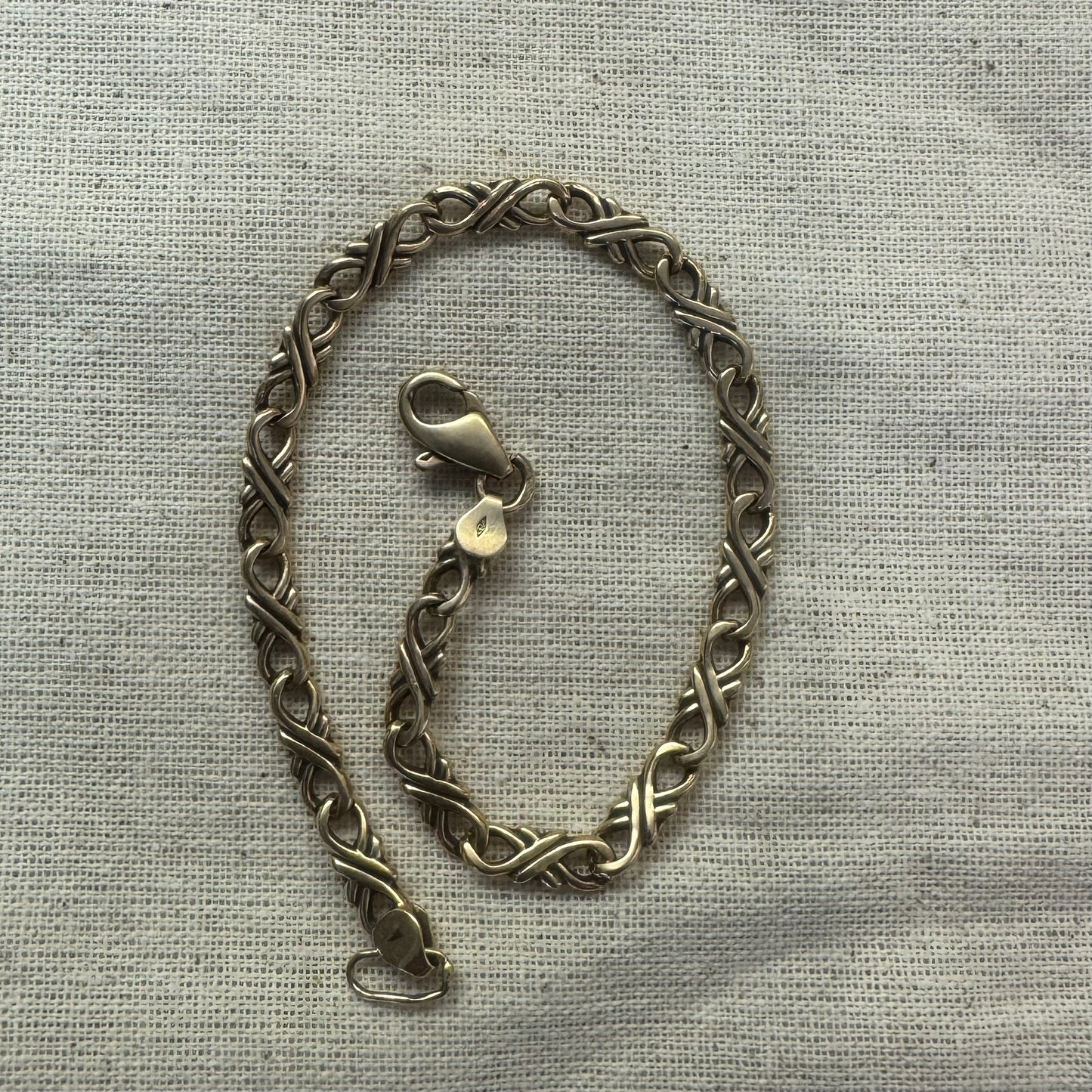 צמיד זהב צהוב 14 קראט עם חוליות שזורות בעיצוב שזירה ופיתול, וסוגר מסוג לובסטר.