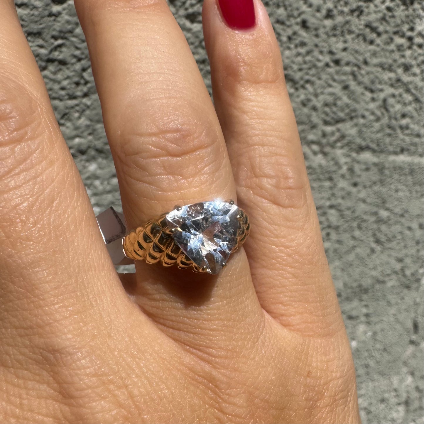 10K gold ring featuring a large, triangular-cut transparent gemstone set in a bold textured band