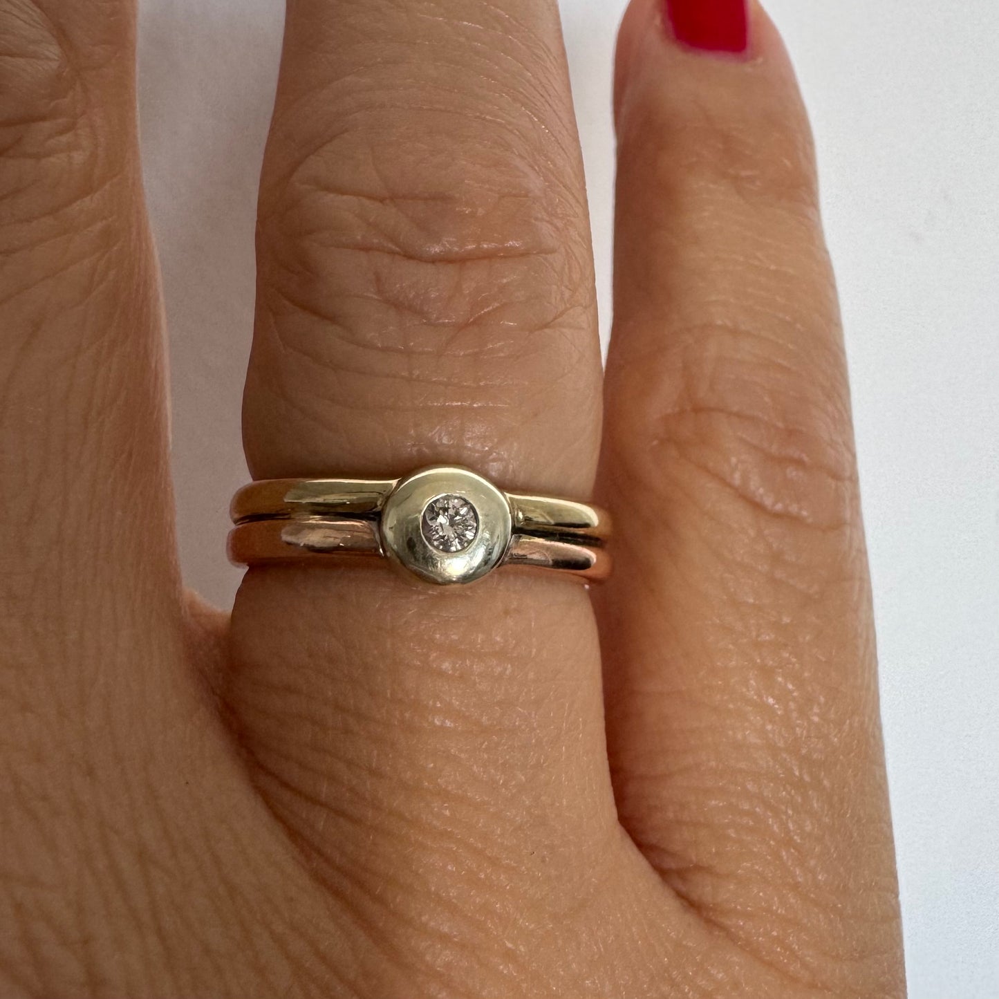 טבעת זהב 10 קראט בעיצוב מינימליסטי ונקי, משובצת יהלום מרכזי במסגרת חלקה (Bezel).