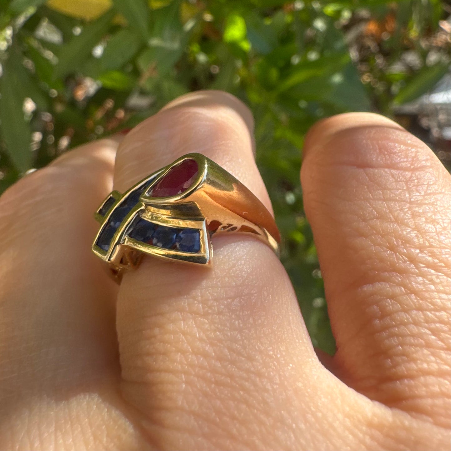 10K gold ring set with a pear-shaped Ruby and deep blue Sapphires in a geometric design.