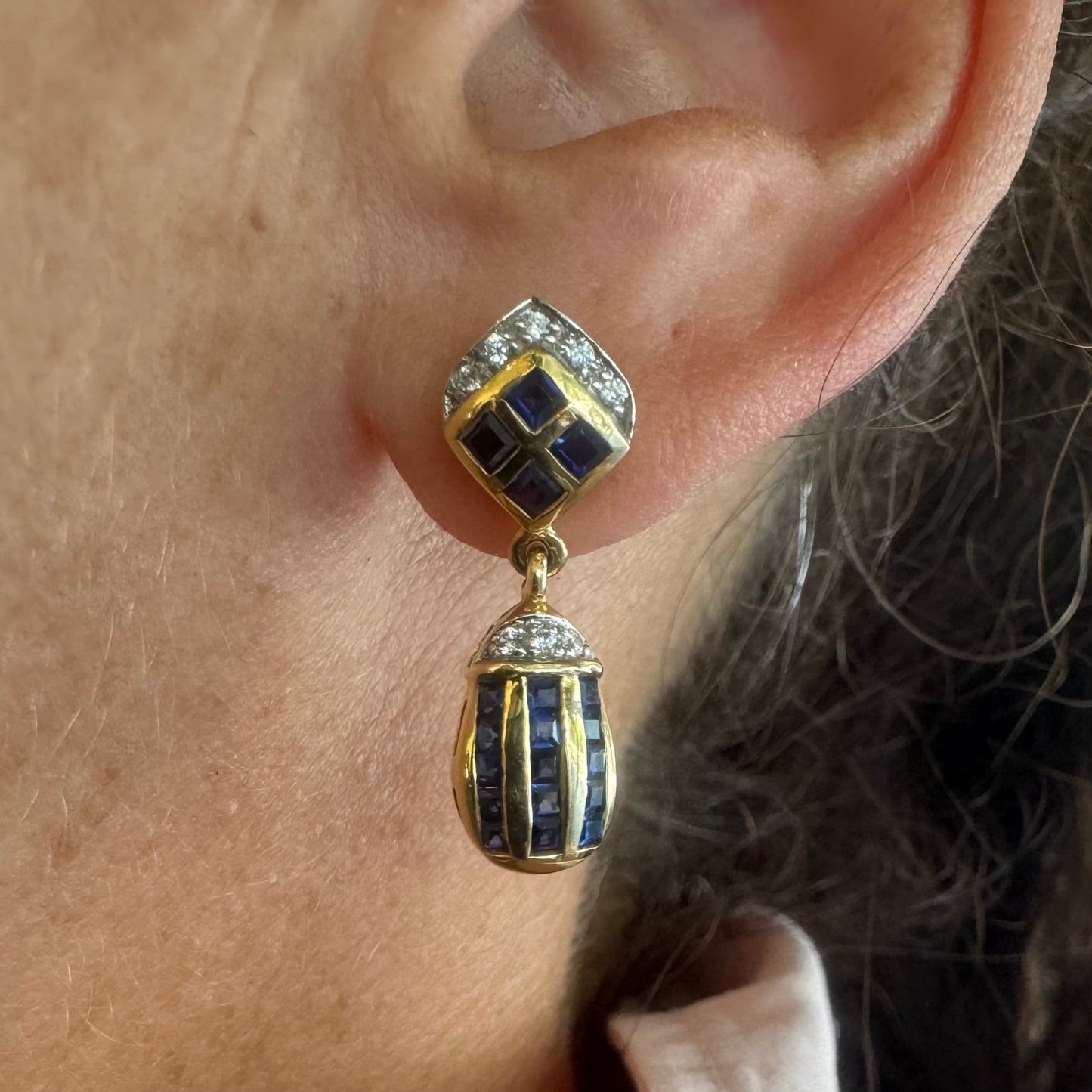 עגילי זהב צהוב 18 קראט תלויים, משובצים אבני ספיר כחולות בגוון כחול עמוק בעיצוב גיאומטרי, בשילוב יהלומים מנצנצים
