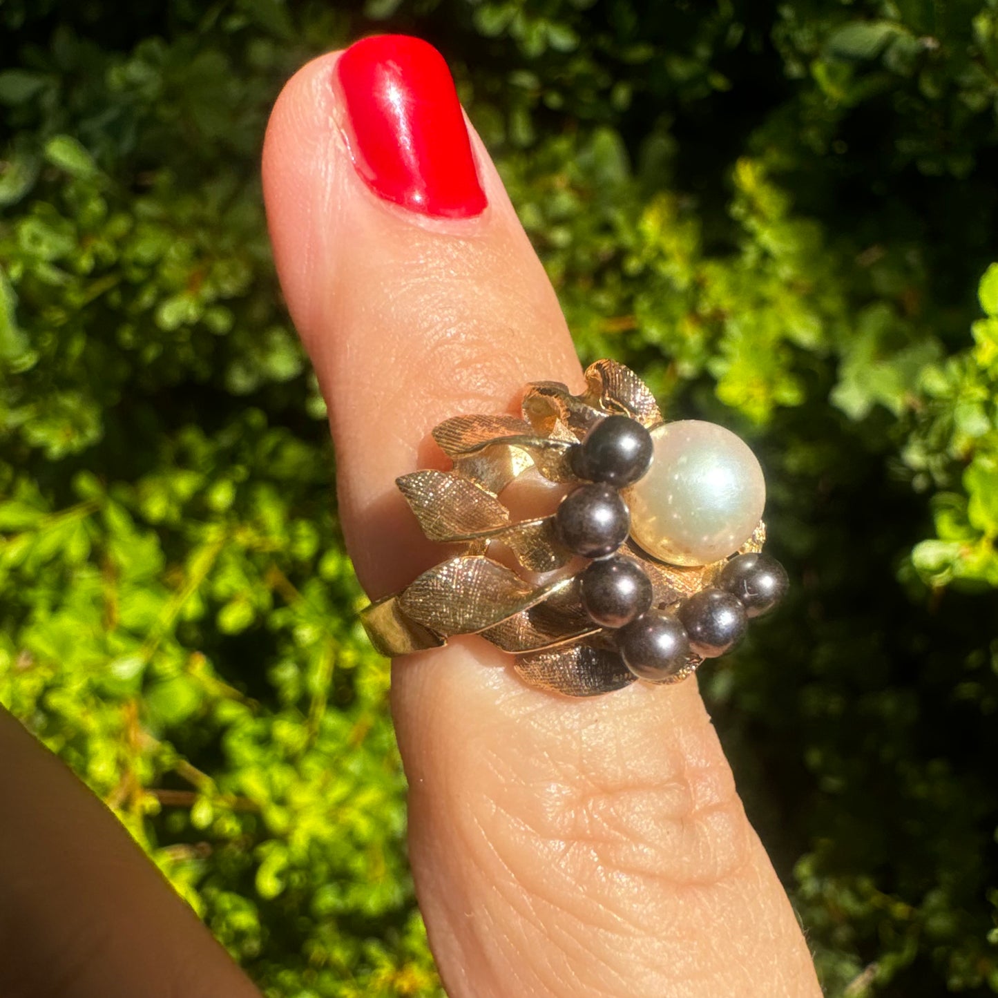 14K gold ring set with a luminous white Pearl at its center surrounded by a delicate circle of black Pearls.