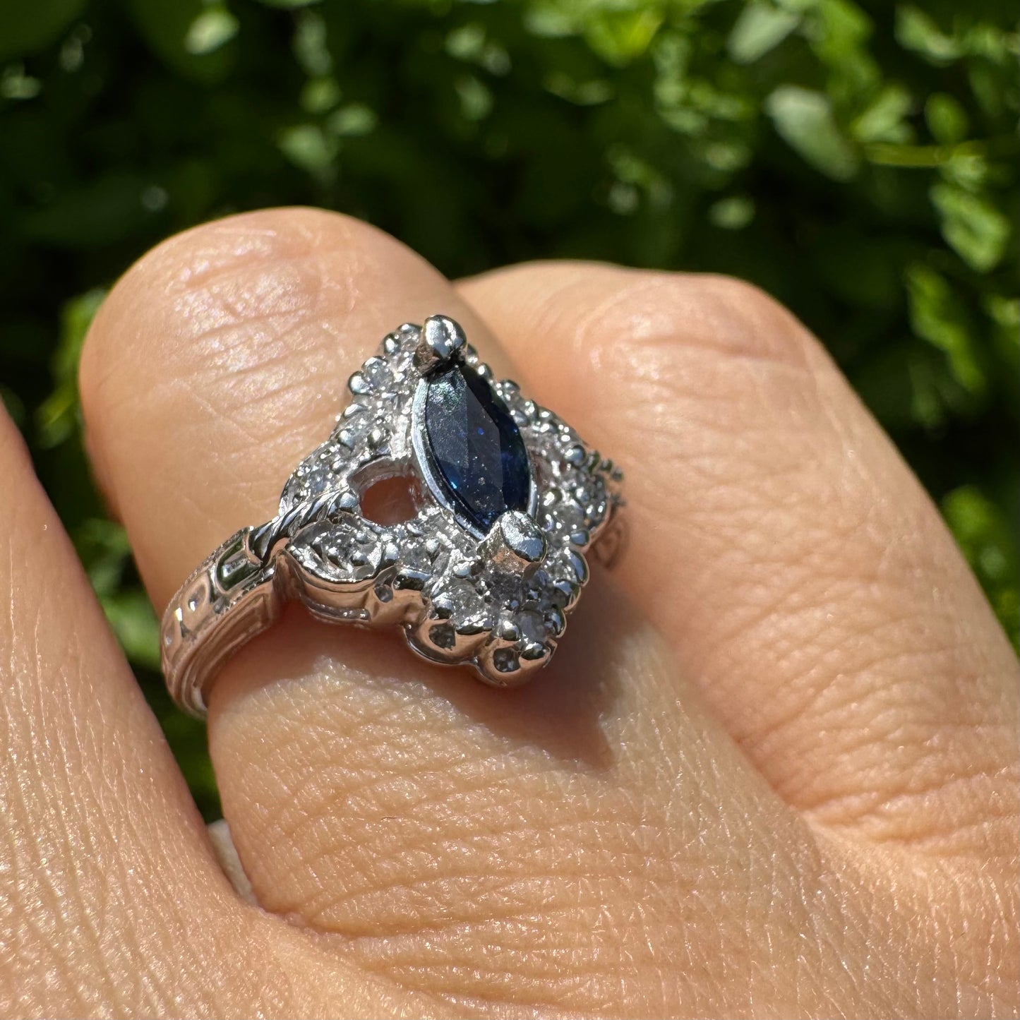 14K gold ring set with a marquise-cut Sapphire at its center, framed by an intricate halo of sparkling Diamonds