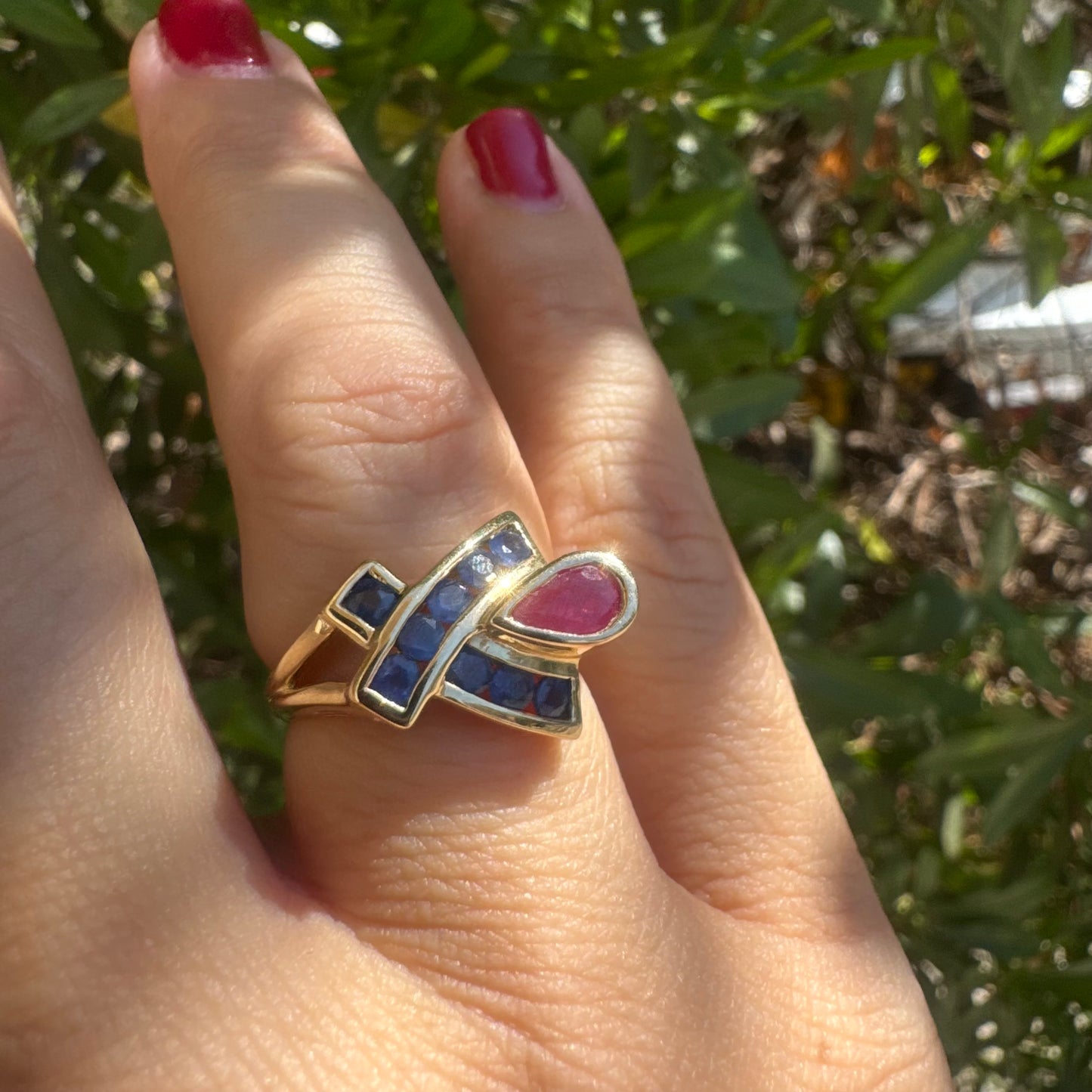 10K gold ring set with a pear-shaped Ruby and deep blue Sapphires in a geometric design.