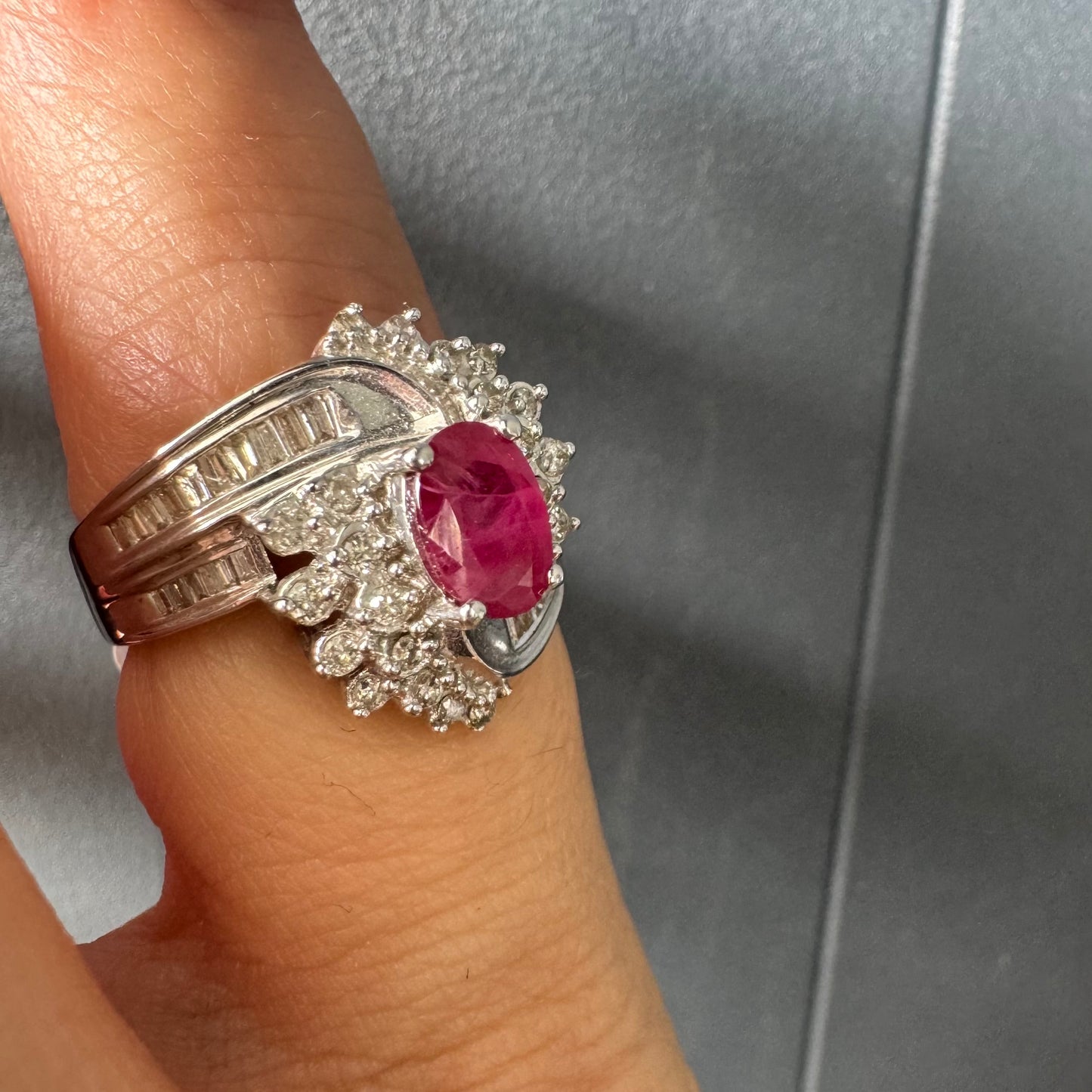 טבעת זהב 14 קראט משובצת אבן רובי אובלית בגוון אדום עמוק ומלא חיים ומוקפת הילה עשירה של יהלומים עגולים, המעניקים ברק ונוכחות מרשימה