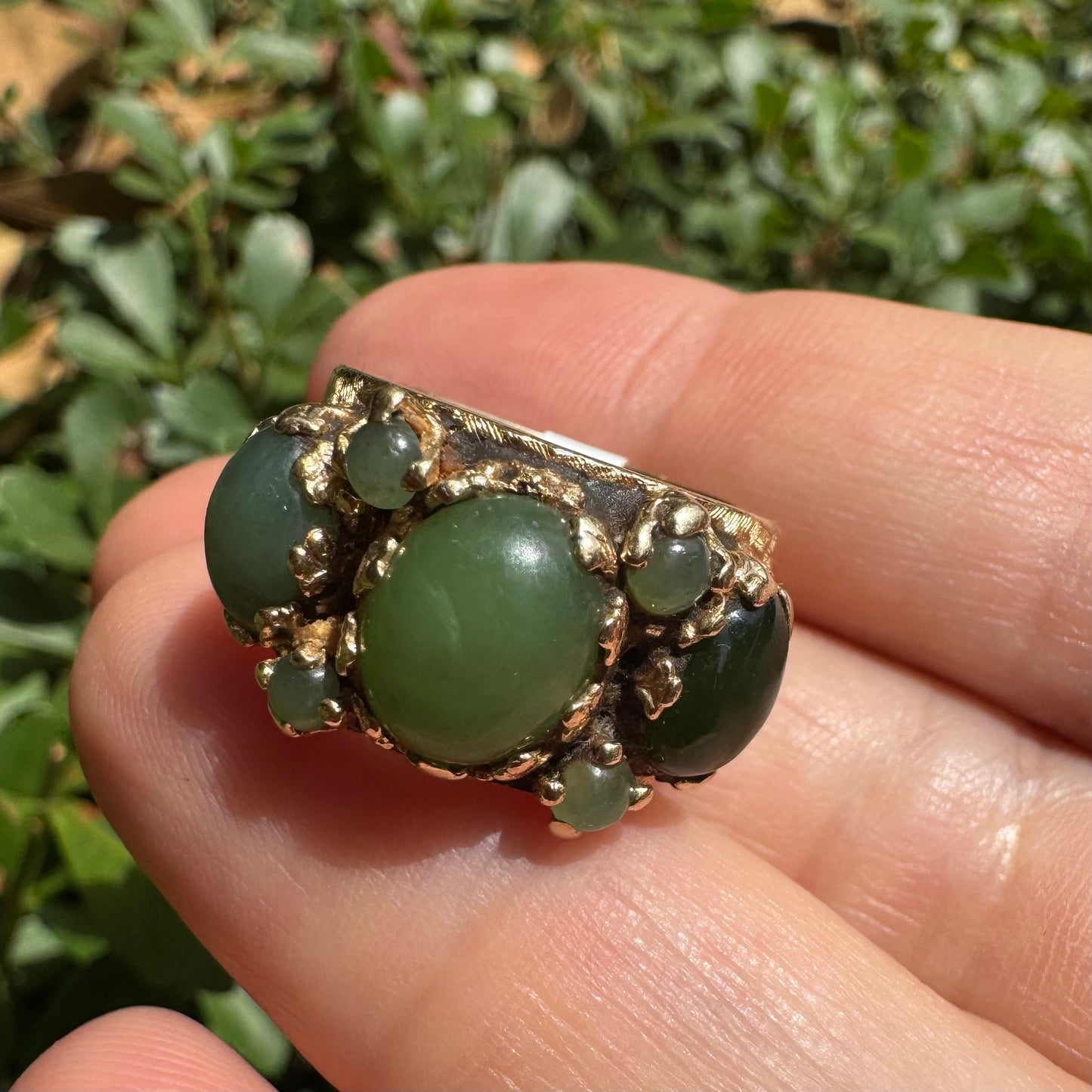 14K gold ring set with a central oval green Jade cabochon, framed by additional Jade stones in varying shades and sizes