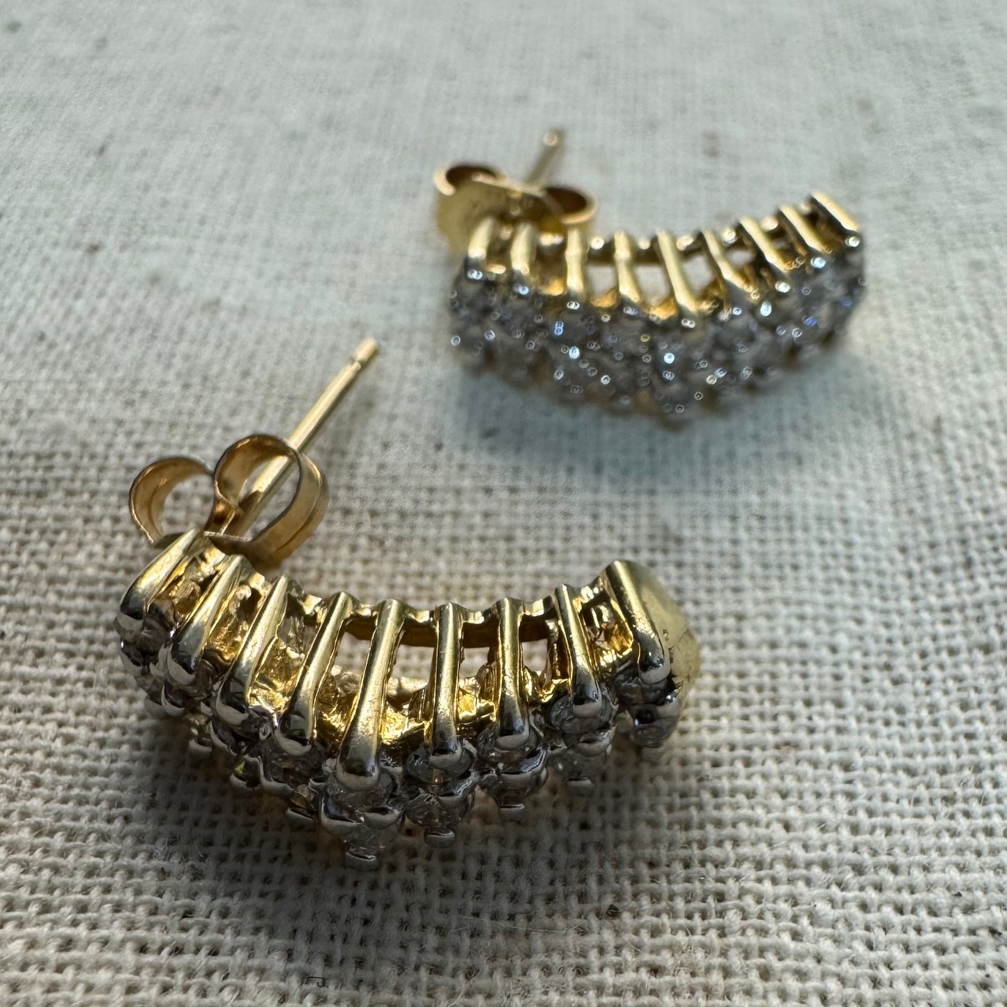 עגילי זהב צהוב 14 קראט בעיצוב חצי חישוק, משובצים יהלומים מנצנצים בשיבוץ צפוף המעניק מראה עשיר ונוכח.