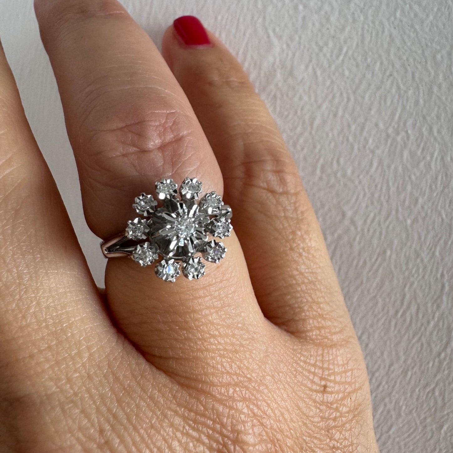 טבעת זהב 18 קראט משובצת יהלום מרכזי מוקף יהלומים נוספים בעיצוב פרח סימטרי ומרשים