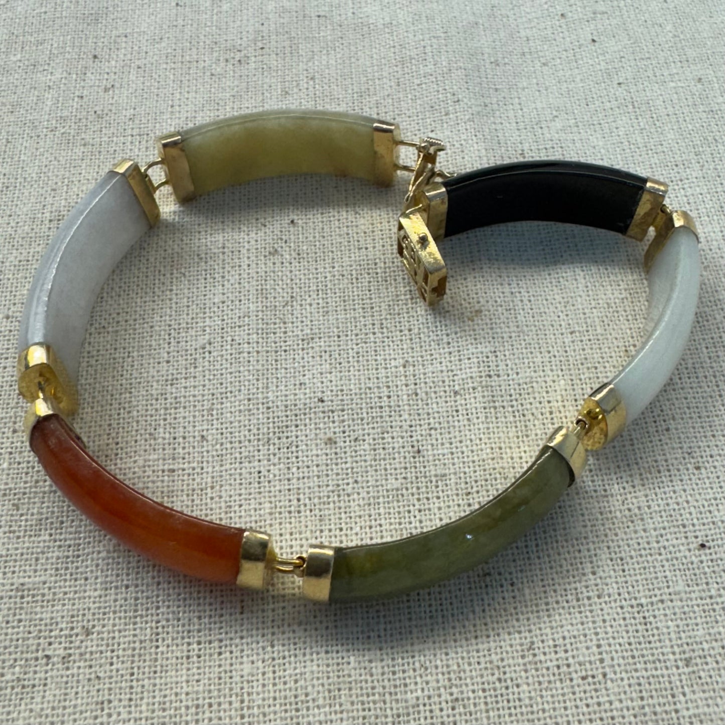 צמיד זהב צהוב 14 קראט עשוי מקטעי ג’ייד (jade) בשלושה גוונים – ירקרק, לבן ואדום – בשיבוץ זהב.