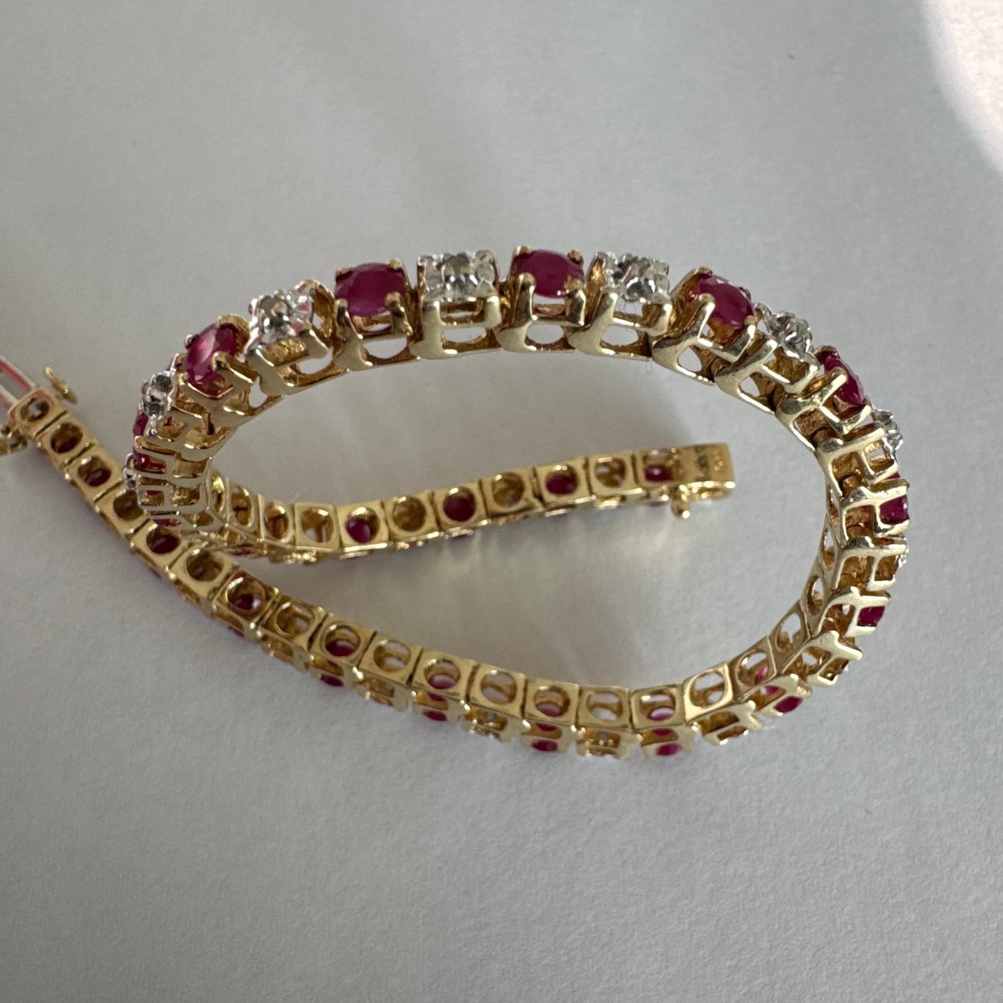 צמיד זהב צהוב 10 קראט משובץ אבני רובי בגוון אדום עמוק וביניהן יהלומים לבנים מנצנצים.