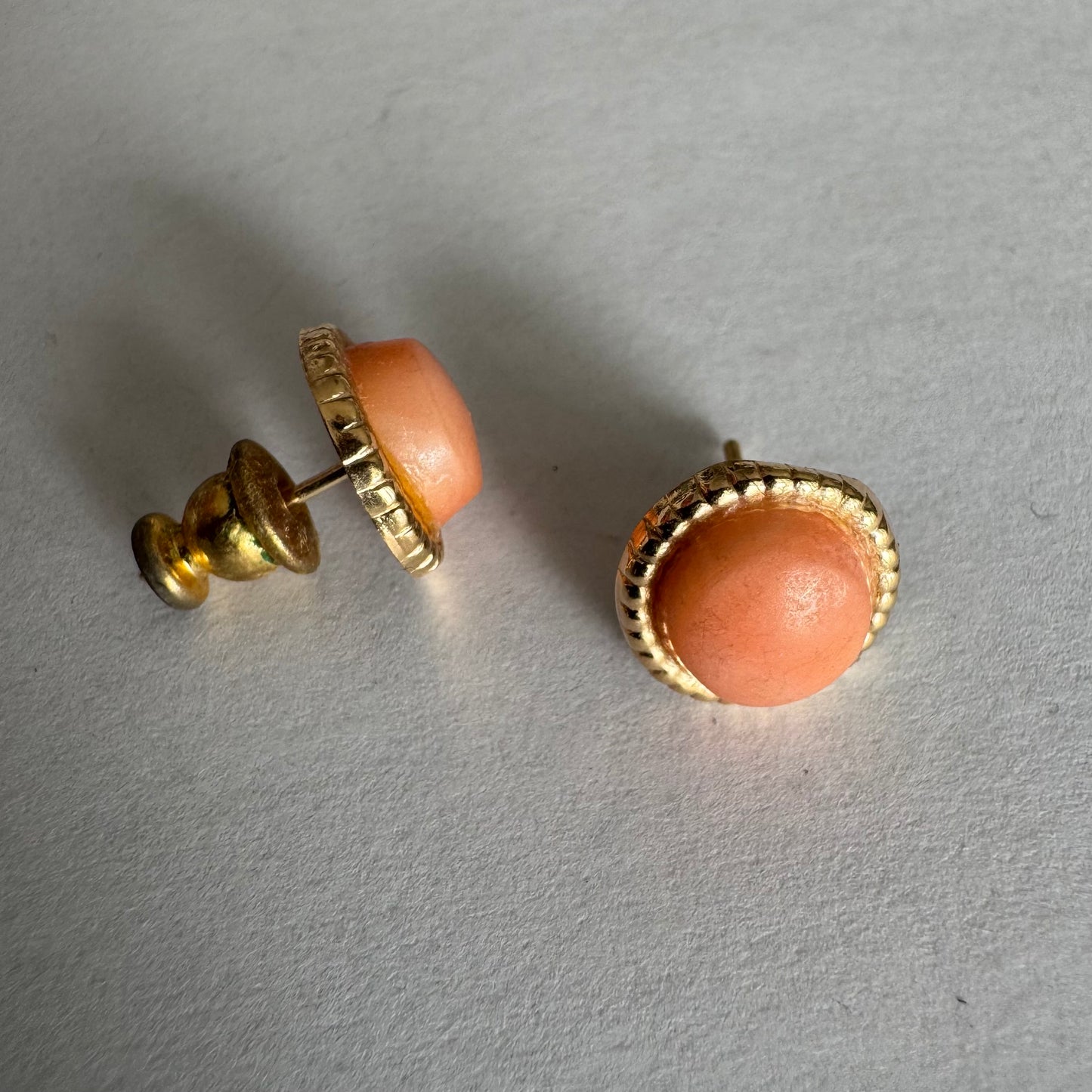 14K gold stud earrings set with natural Coral stones in a soft peach-pink tone.