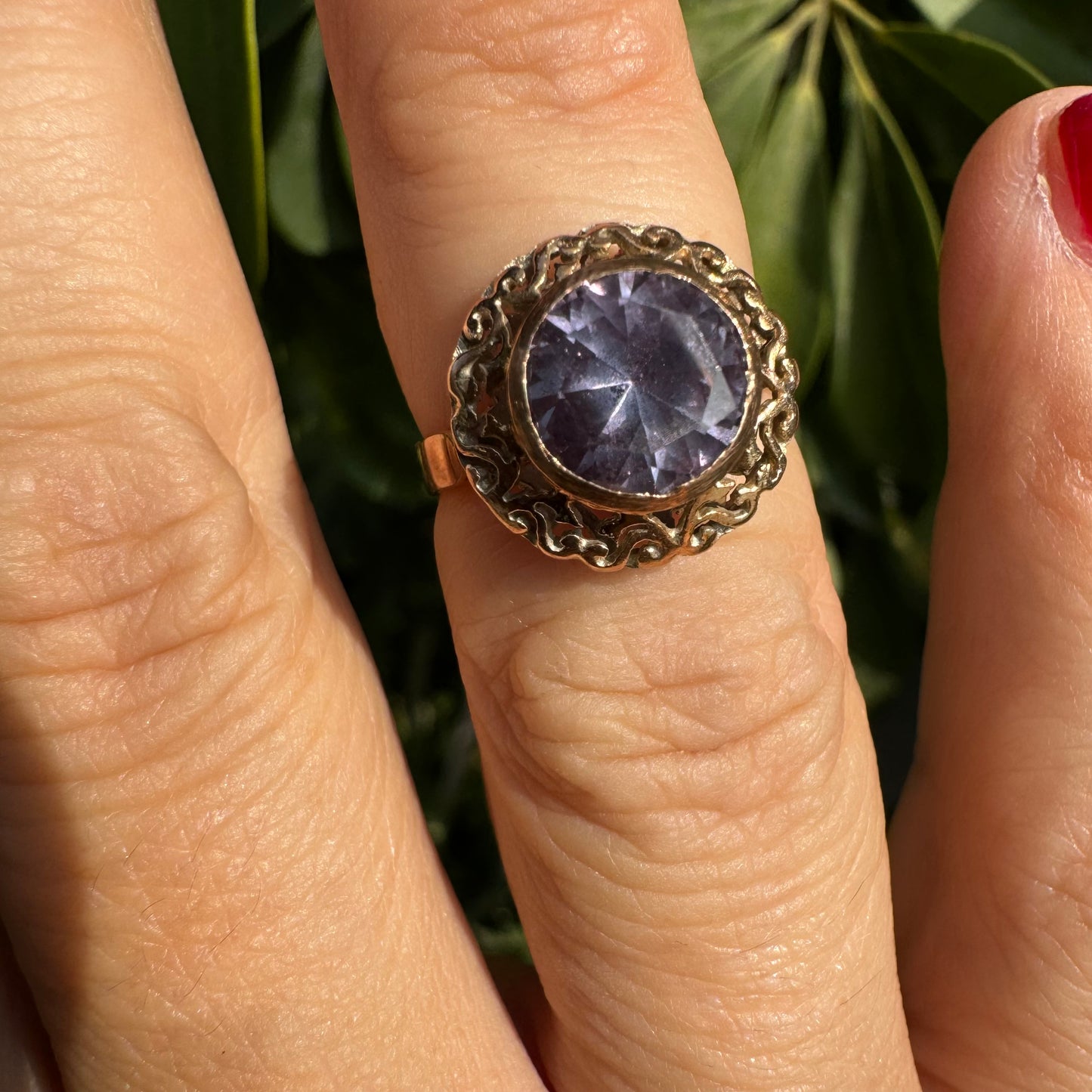 14K gold ring set with a large round-cut Tanzanite framed by an ornate filigree bezel