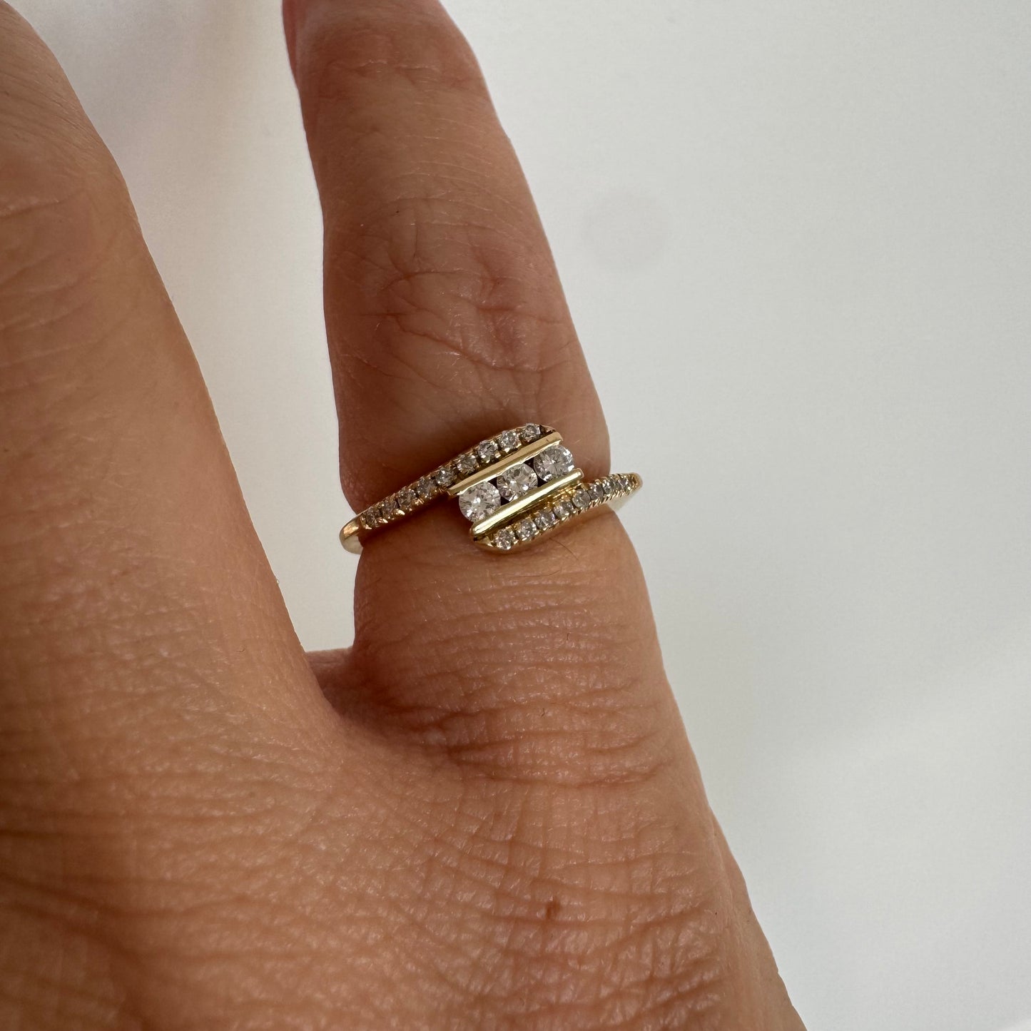 טבעת זהב צהוב 14 קראט בעיצוב ייחודי, משובצת שלושה יהלומים מרכזיים ושורות נוספות של יהלומים לאורך הזרועות. 