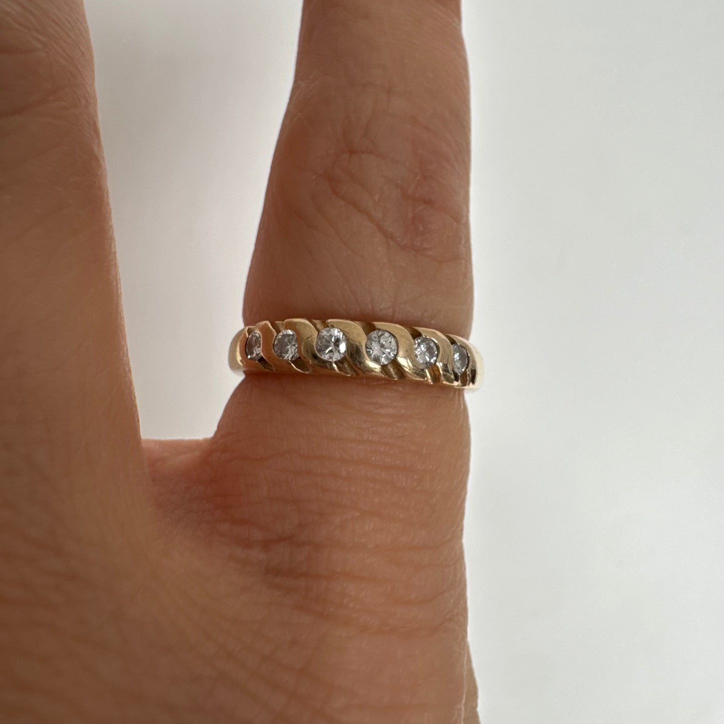 טבעת זהב צהוב 14 קראט משובצת יהלומים בחיתוך עגול, בשיבוץ מחורץ היוצר מראה ייחודי ומלא תנועה.