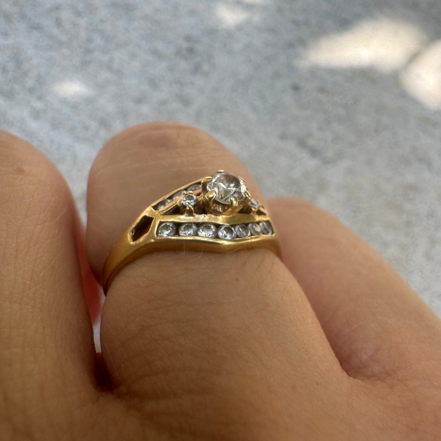 18K gold ring set with a central round Diamond, surrounded by rows of Diamonds in a decorative setting.