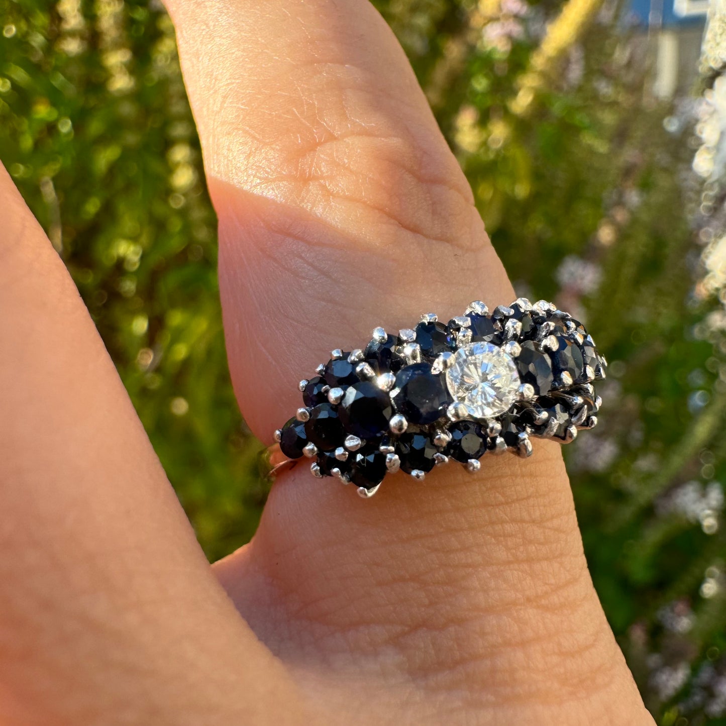 18K gold ring set with a brilliant-cut central Diamond, surrounded by a striking cluster of deep blue Sapphires.