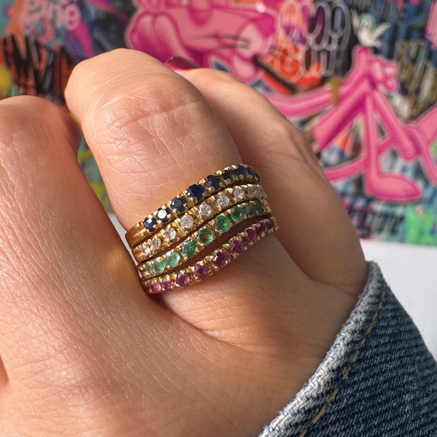 טבעת זהב צהוב 18 קראט, משובצת בשורות צבעוניות של ספירים, אמרלדים, רובינים ויהלומים – פריט אלגנטי מלא חיים וזוהר.
