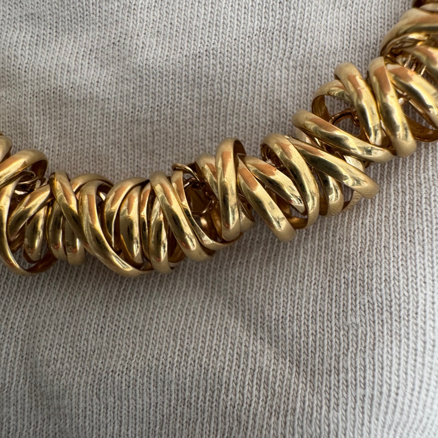 14K gold necklace featuring a series of intertwined gold rings creating a bold and sculptural design.