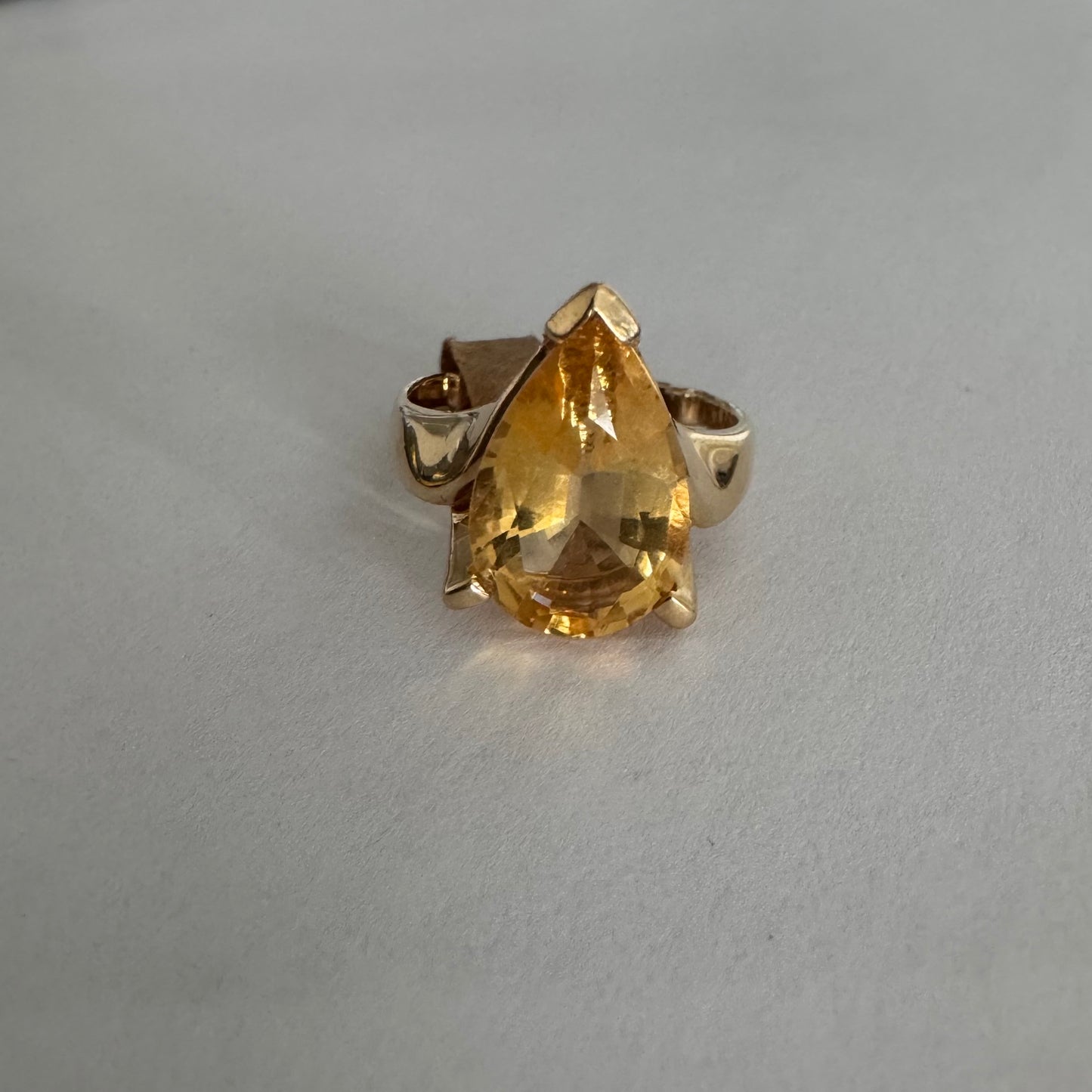 טבעת זהב צהוב 14 קראט משובצת באבן סיטרין גדולה בחיתוך טיפה, עם זהב שמחבק אותה בצורה פתוחה ומודרנית.