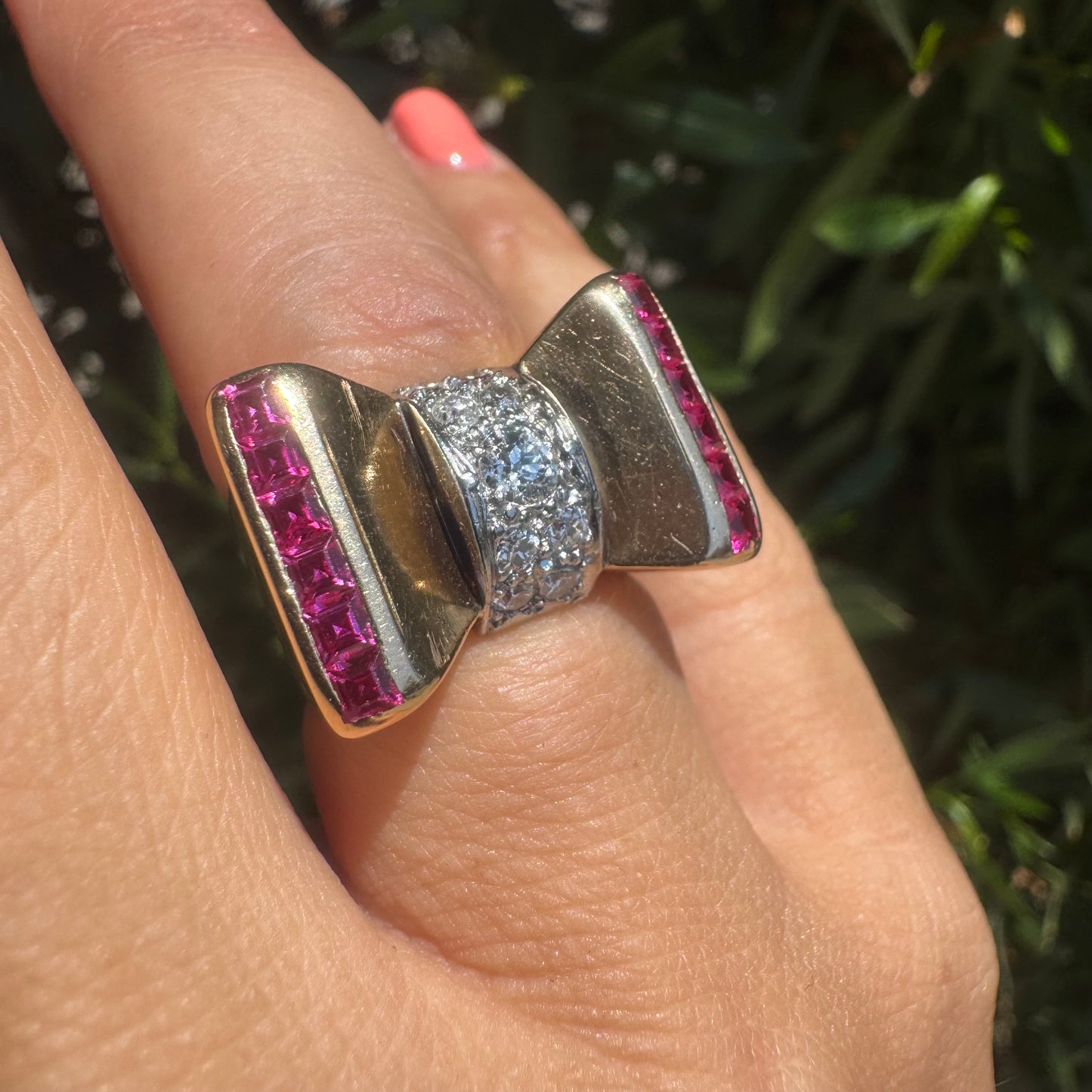 18K gold bow-shaped ring set with pavé Diamonds at the center and rows of square-cut Rubies on the sides.