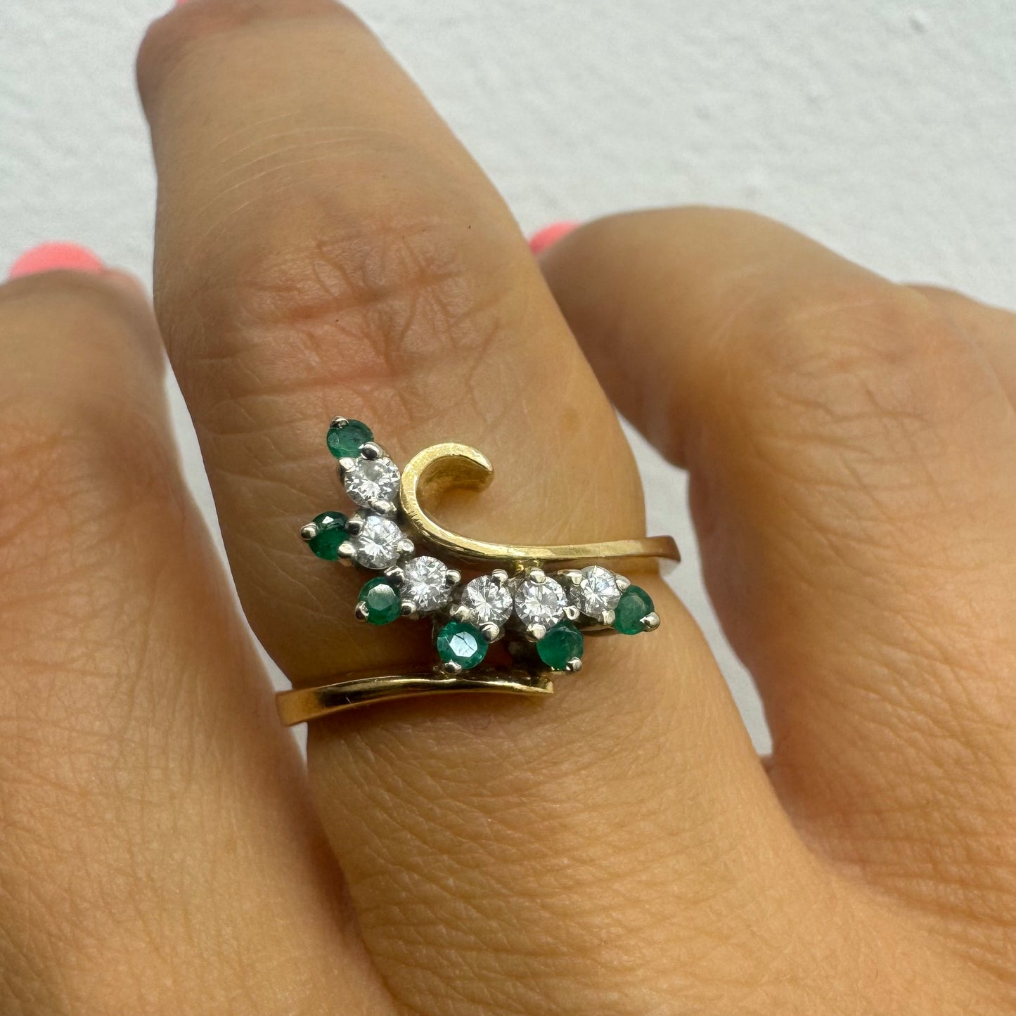 14K gold open ring featuring a delicate swirl set with Emeralds and brilliant-cut Diamonds
