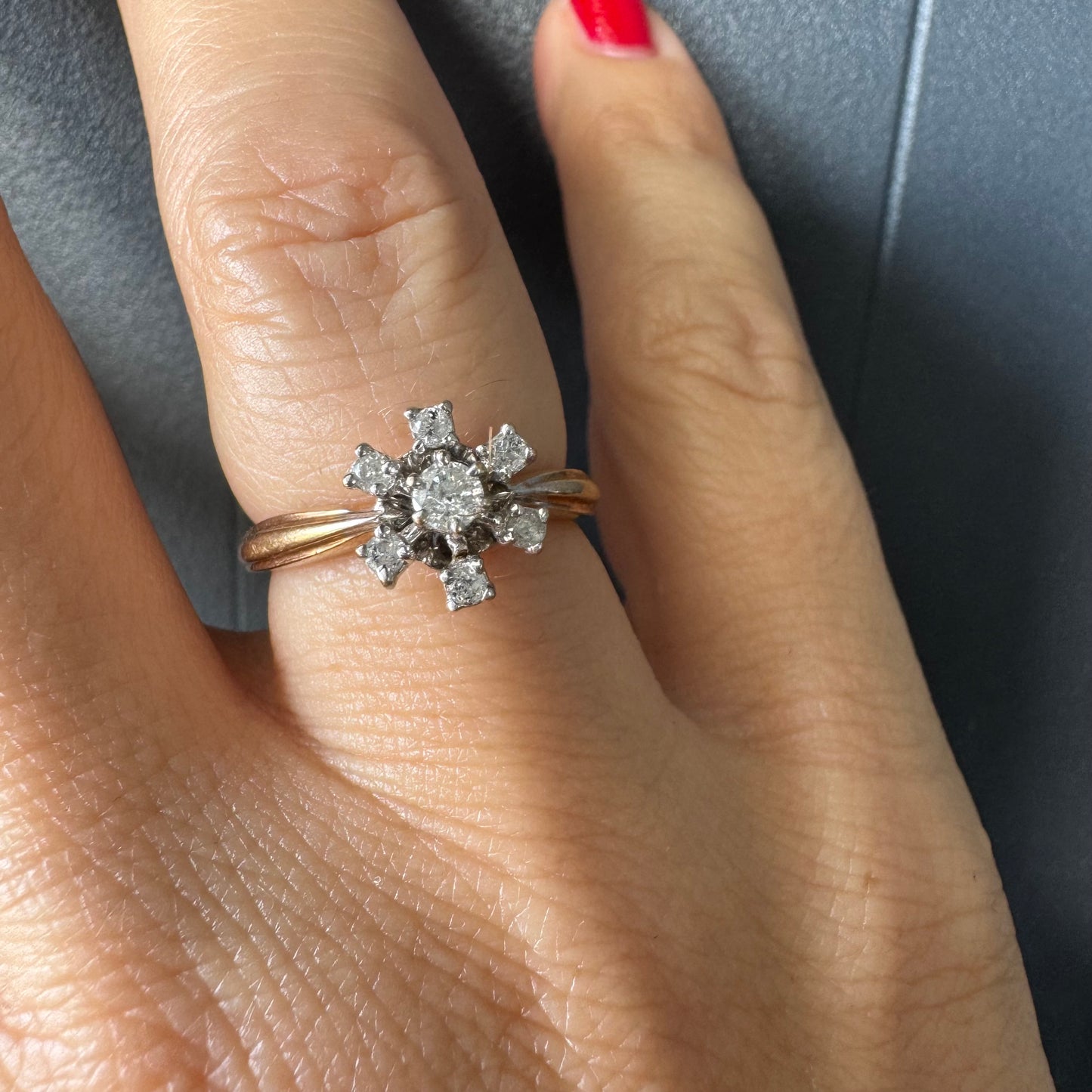 טבעת זהב 9 קראט משובצת יהלום מרכזי ויהלומים מסביב בעיצוב פרח קלאסי.