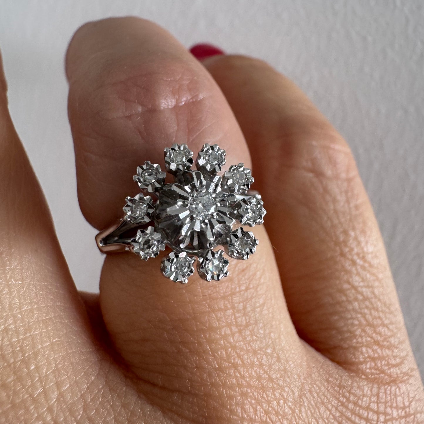 טבעת זהב 18 קראט משובצת יהלום מרכזי מוקף יהלומים נוספים בעיצוב פרח סימטרי ומרשים