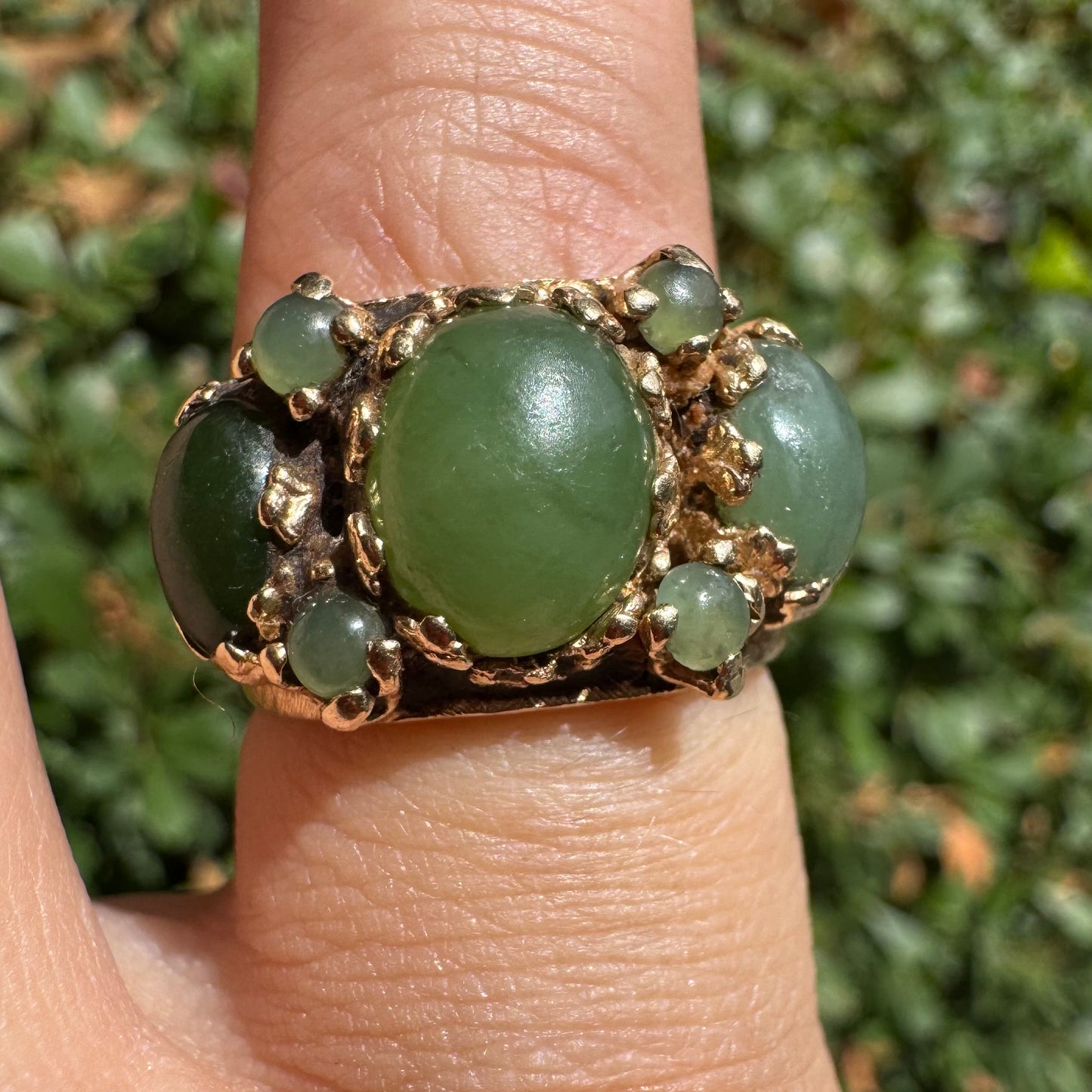 14K gold ring set with a central oval green Jade cabochon, framed by additional Jade stones in varying shades and sizes