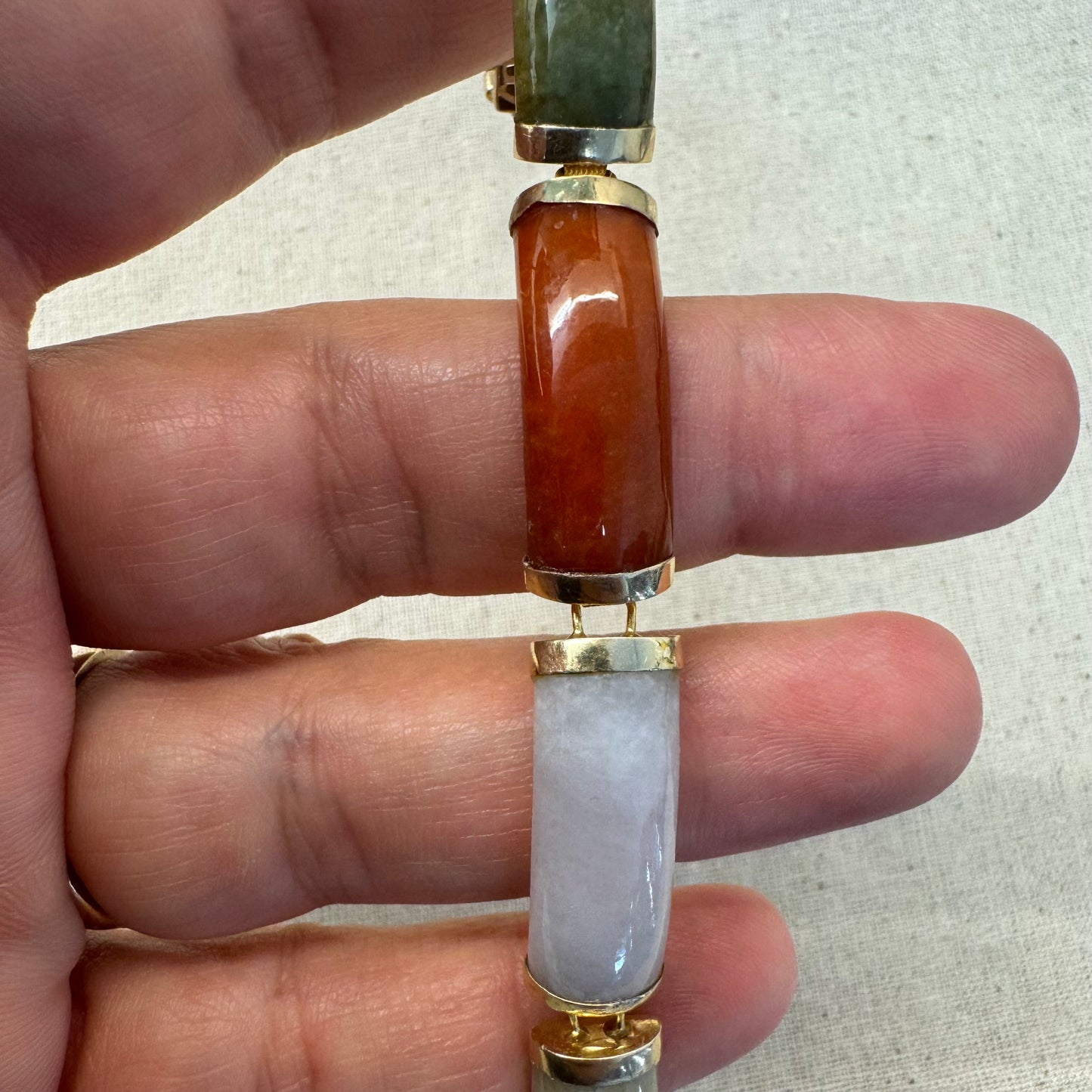 צמיד זהב צהוב 14 קראט עשוי מקטעי ג’ייד (jade) בשלושה גוונים – ירקרק, לבן ואדום – בשיבוץ זהב.