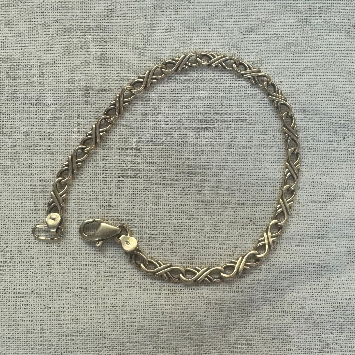 צמיד זהב צהוב 14 קראט עם חוליות שזורות בעיצוב שזירה ופיתול, וסוגר מסוג לובסטר.