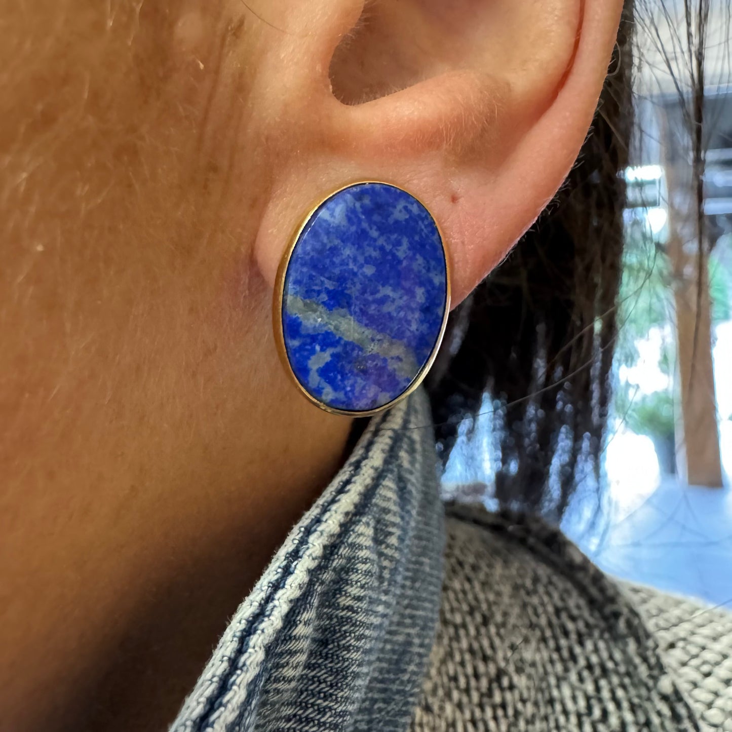 14K gold stud earrings set with polished oval Lapis Lazuli stones in a sleek gold bezel setting.