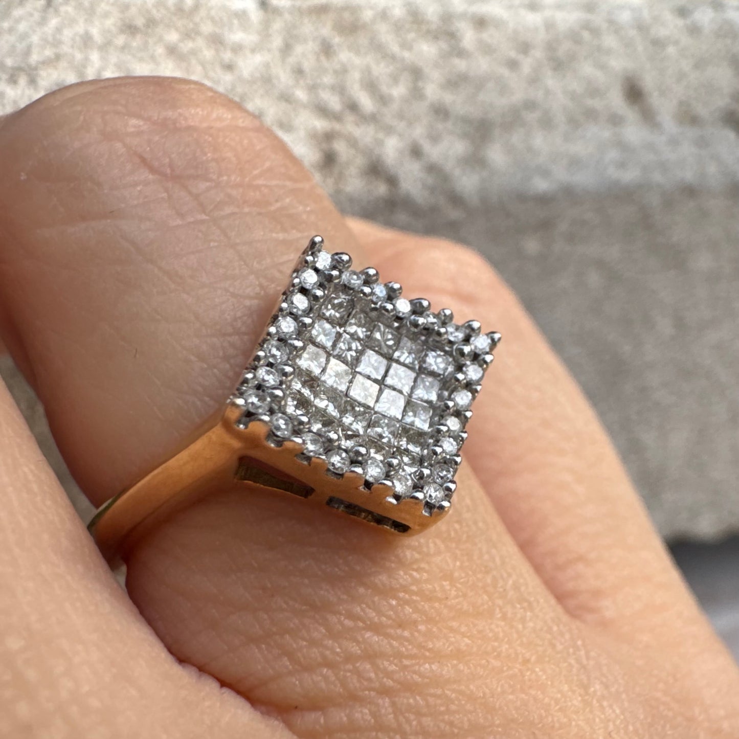 טבעת זהב 14 קראט בעיצוב ריבועי משובצת יהלומים בחיתוך פרינסס ומוקפת מסגרת יהלומים עגולים. 