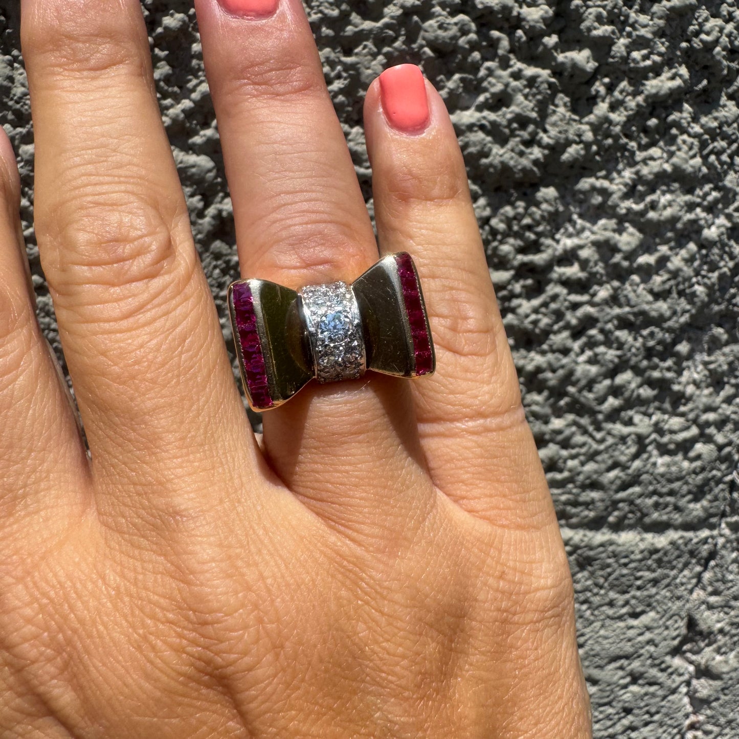18K gold bow-shaped ring set with pavé Diamonds at the center and rows of square-cut Rubies on the sides.