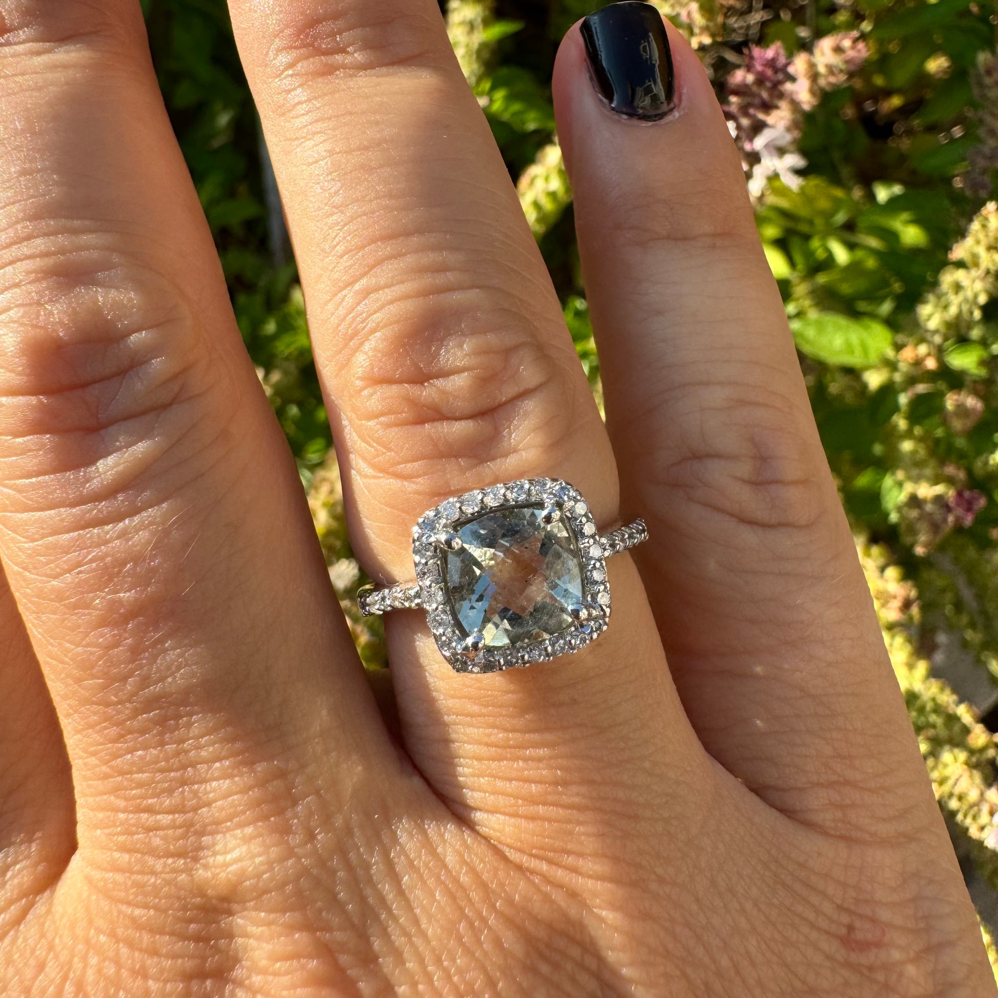 טבעת זהב לבן 14 קראט משובצת באבן אקוומרין בגוון תכלת ומוקפת במסגרת כפולה של יהלומים עגולים מנצנצים.