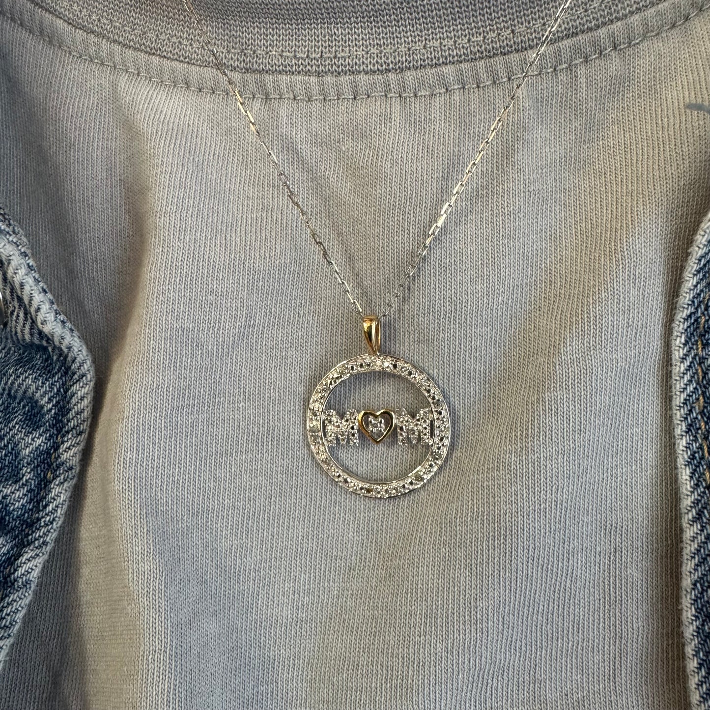 תליון זהב לבן 14 קראט עם הכיתוב ״MOM” מוקף מסגרת יהלומים עדינה.