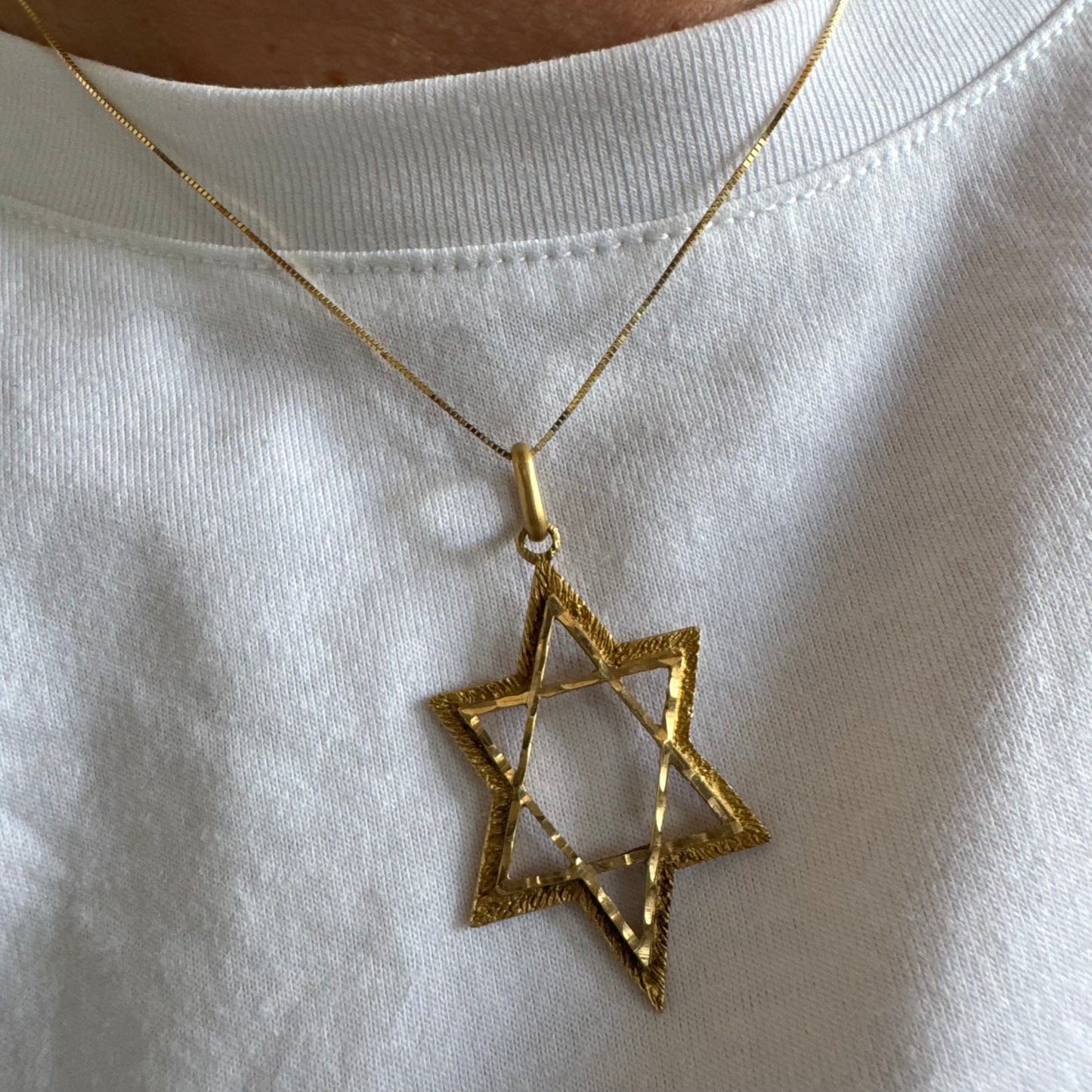 תליון מגן דוד מזהב צהוב 14 קראט בעיצוב פתוח, עם טקסטורה עדינה בשוליים המוסיפה עומק ואופי.