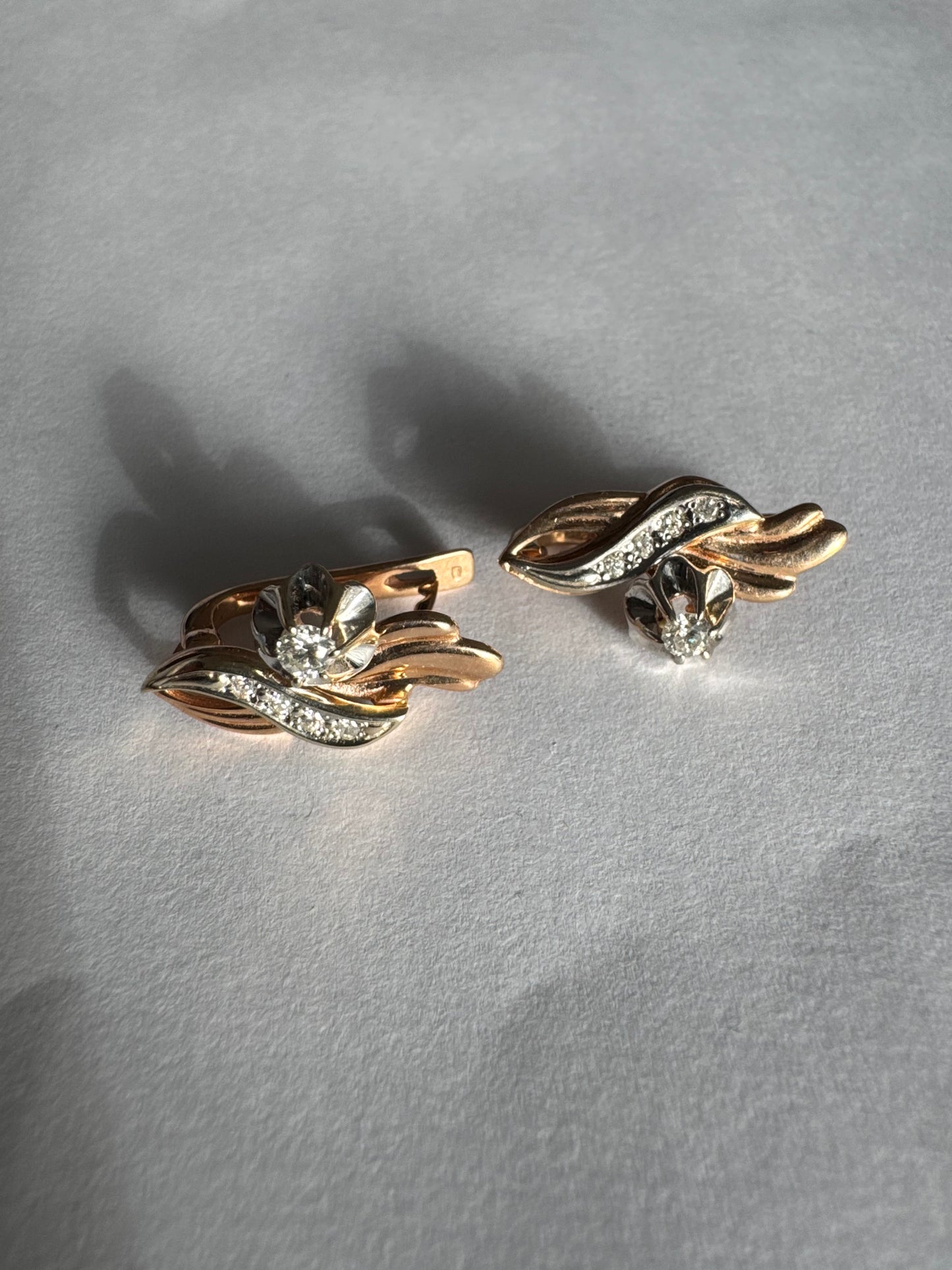 עגילי זהב 14 קראט בעיצוב מתעגל ואלגנטי המשובצים יהלומים נוצצים .