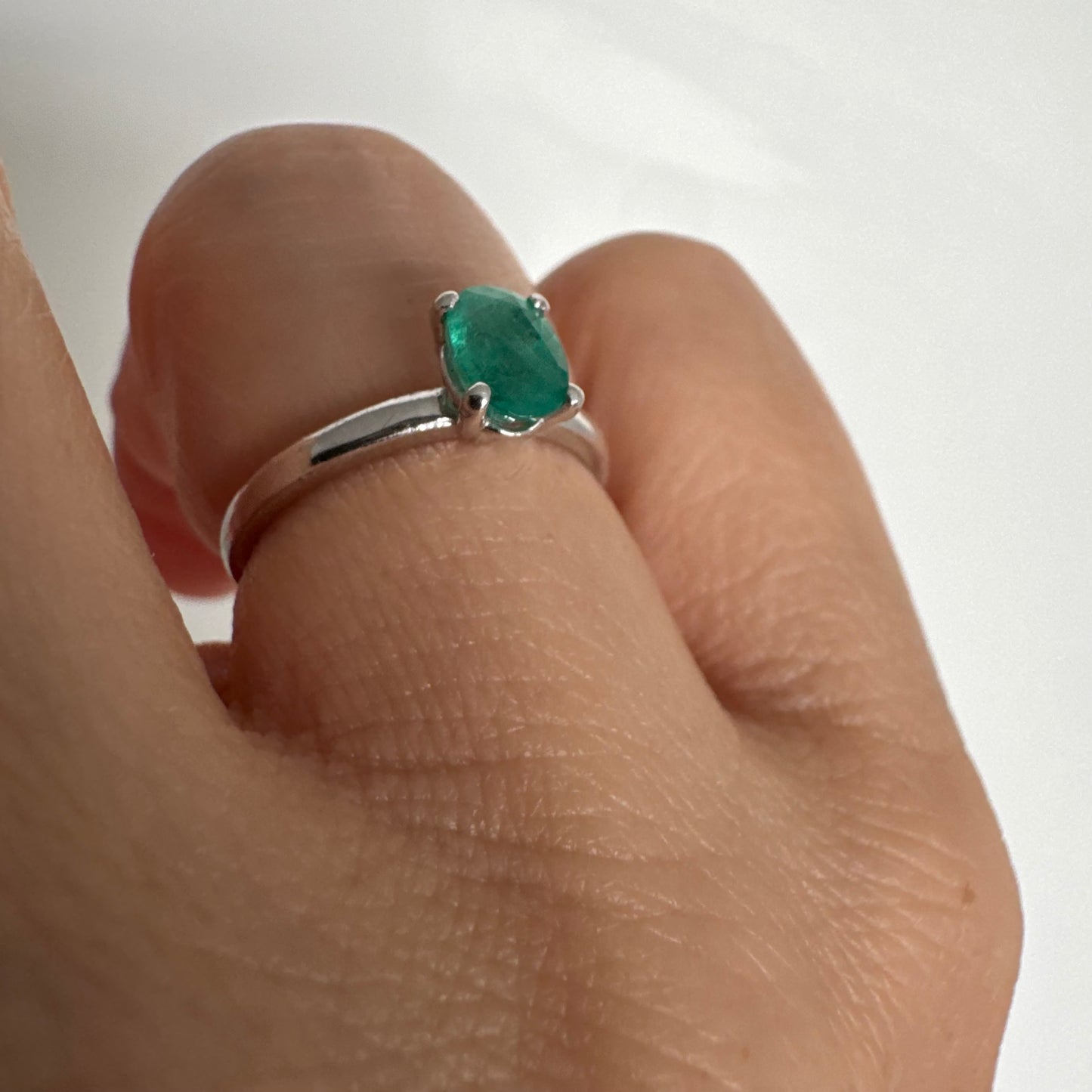 טבעת זהב לבן 14 קראט משובצת אבן אמרלד אובלית בגוון ירוק עשיר.