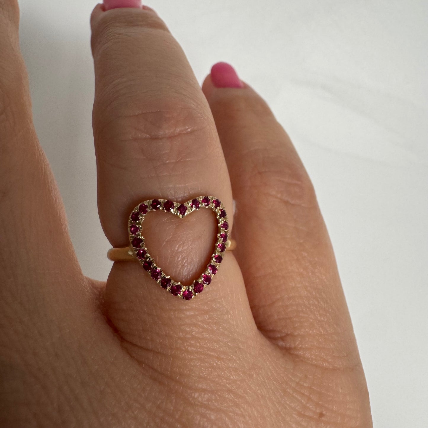 14K yellow gold open-heart ring set with deep red rubies along the frame.