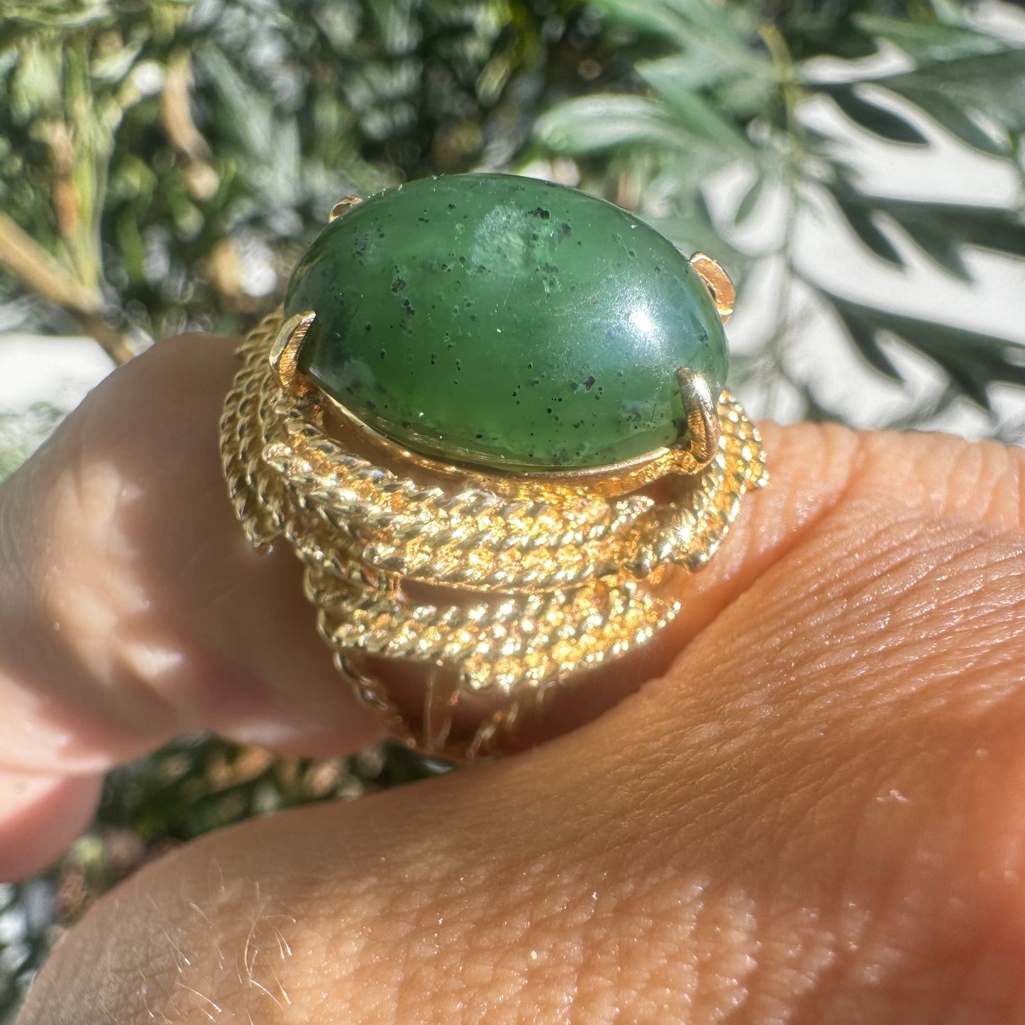 14K gold ring set with a deep green Jade set in a textured gold frame.