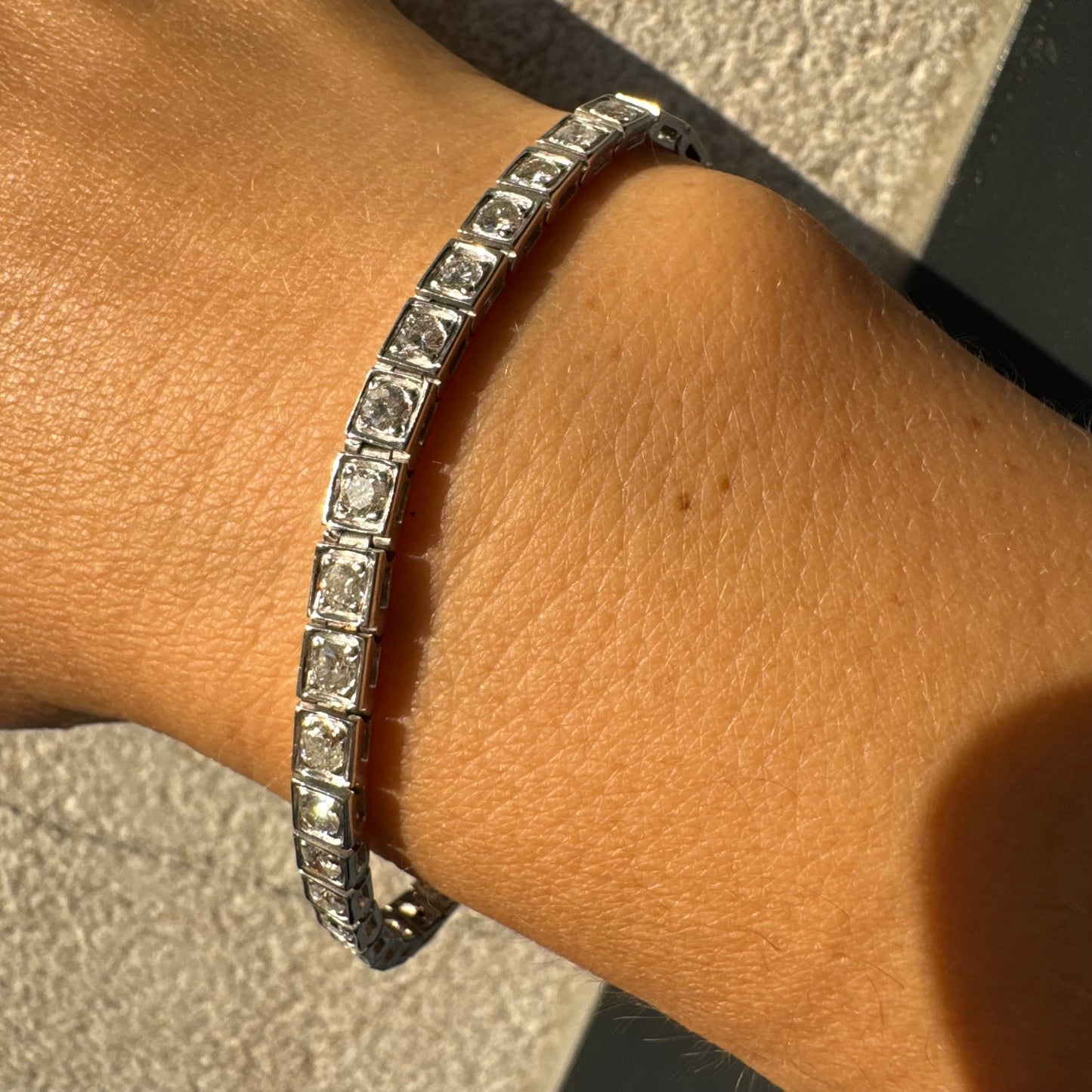 צמיד טניס זהב לבן 18 קראט משובץ יהלומים עגולים נוצצים בתוך מסגרות ריבועיות.