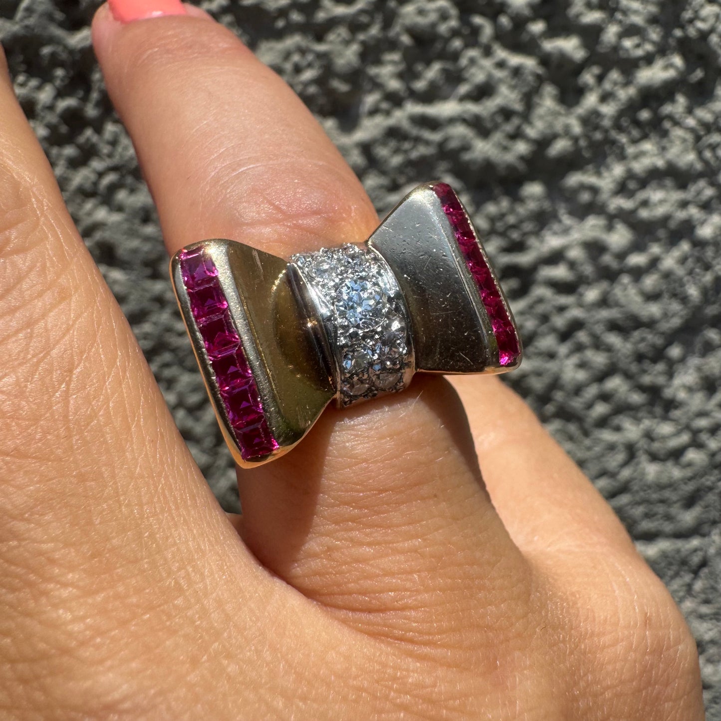 18K gold bow-shaped ring set with pavé Diamonds at the center and rows of square-cut Rubies on the sides.