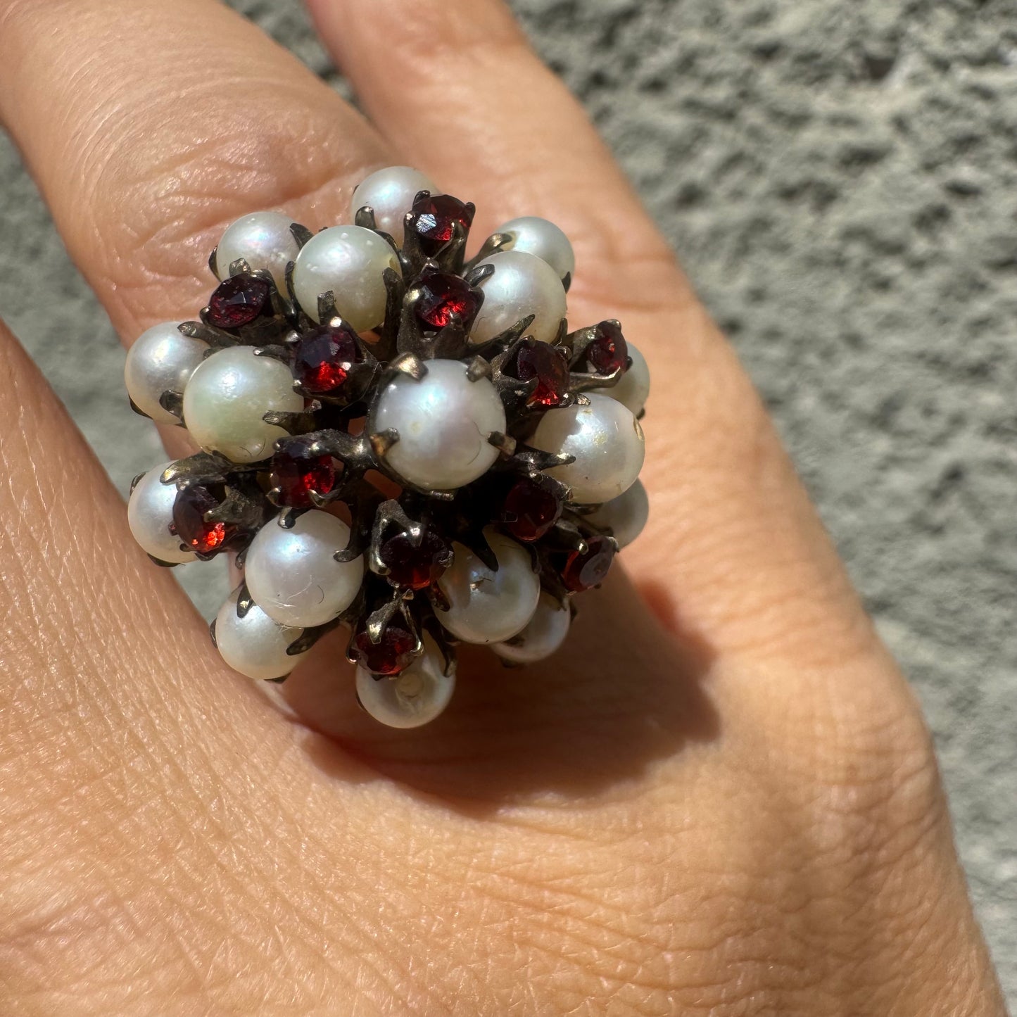 טבעת זהב צהוב 14 קראט משובצת בפנינים טבעיות קטנות ובאבני גרנט אדומות, היוצרות יחד קומפוזיציה עשירה, רומנטית ואומנותית