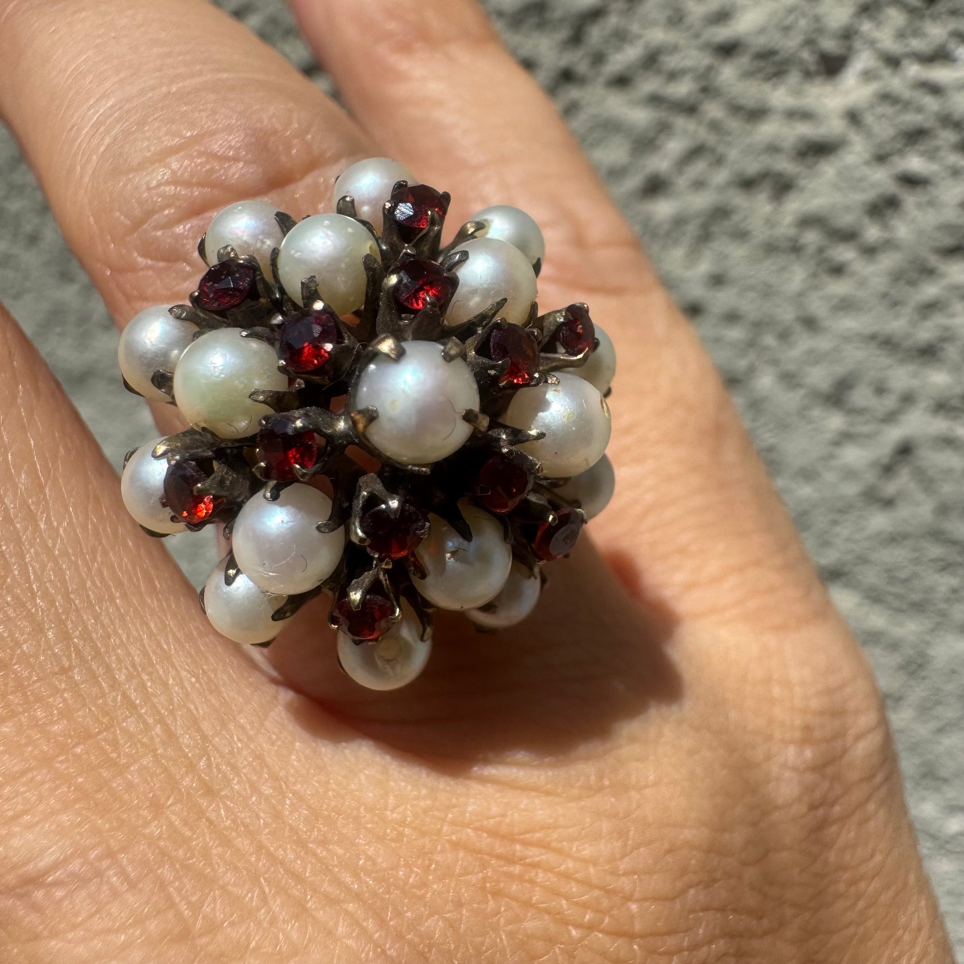 טבעת זהב צהוב 14 קראט משובצת בפנינים טבעיות קטנות ובאבני גרנט אדומות, היוצרות יחד קומפוזיציה עשירה, רומנטית ואומנותית