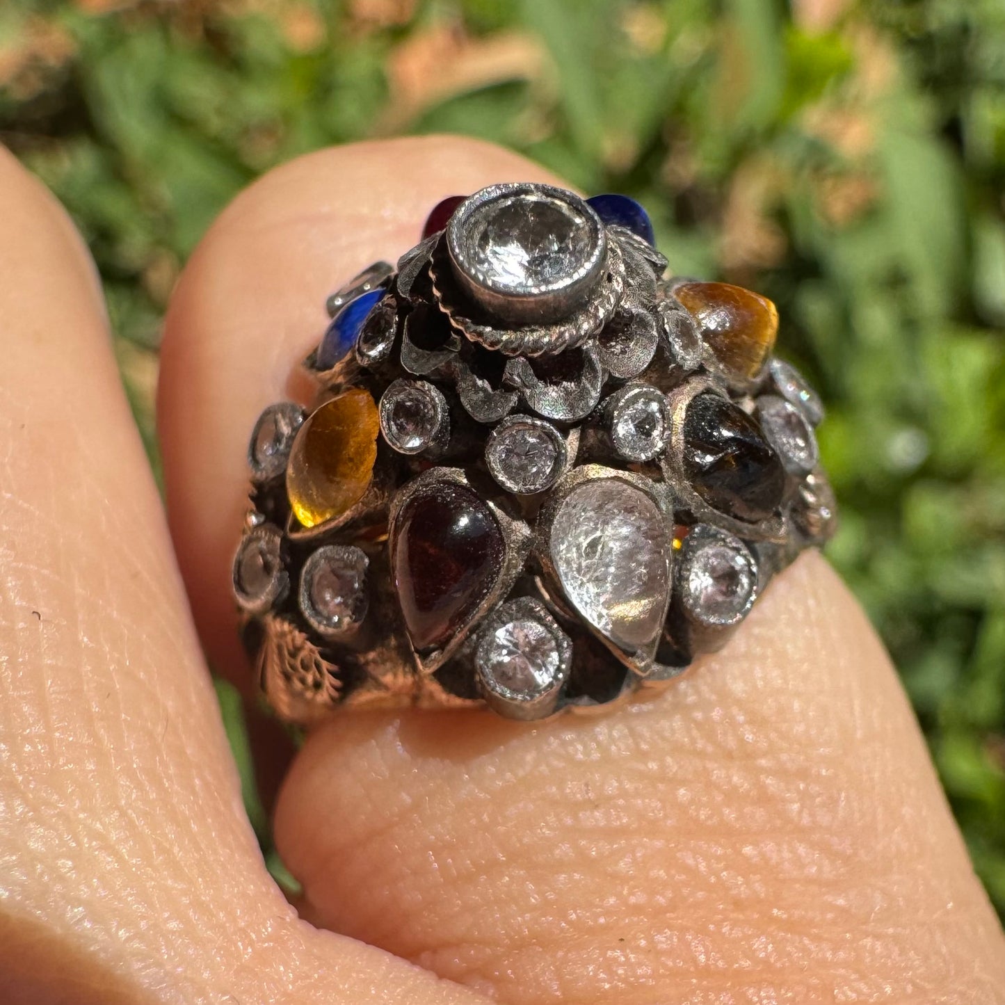 14K gold ring set with a central transparent gemstone surrounded by a vibrant mosaic of colorful gemstones -set in an ornate, handcrafted design