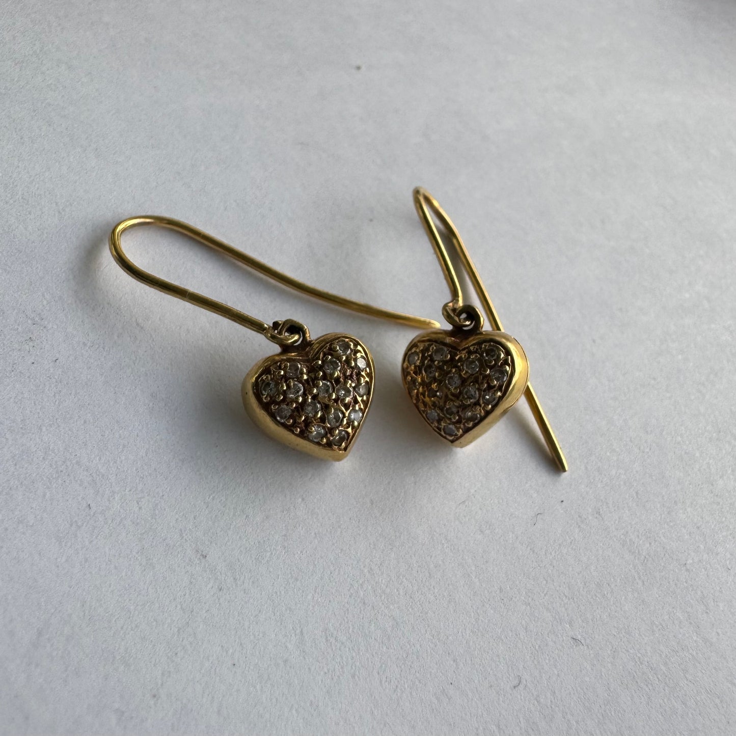 עגילי זהב צהוב 18 קראט תלויים בצורת לב, משובצים יהלומים קטנים המוסיפים ברק עדין ונוכחות אלגנטית.