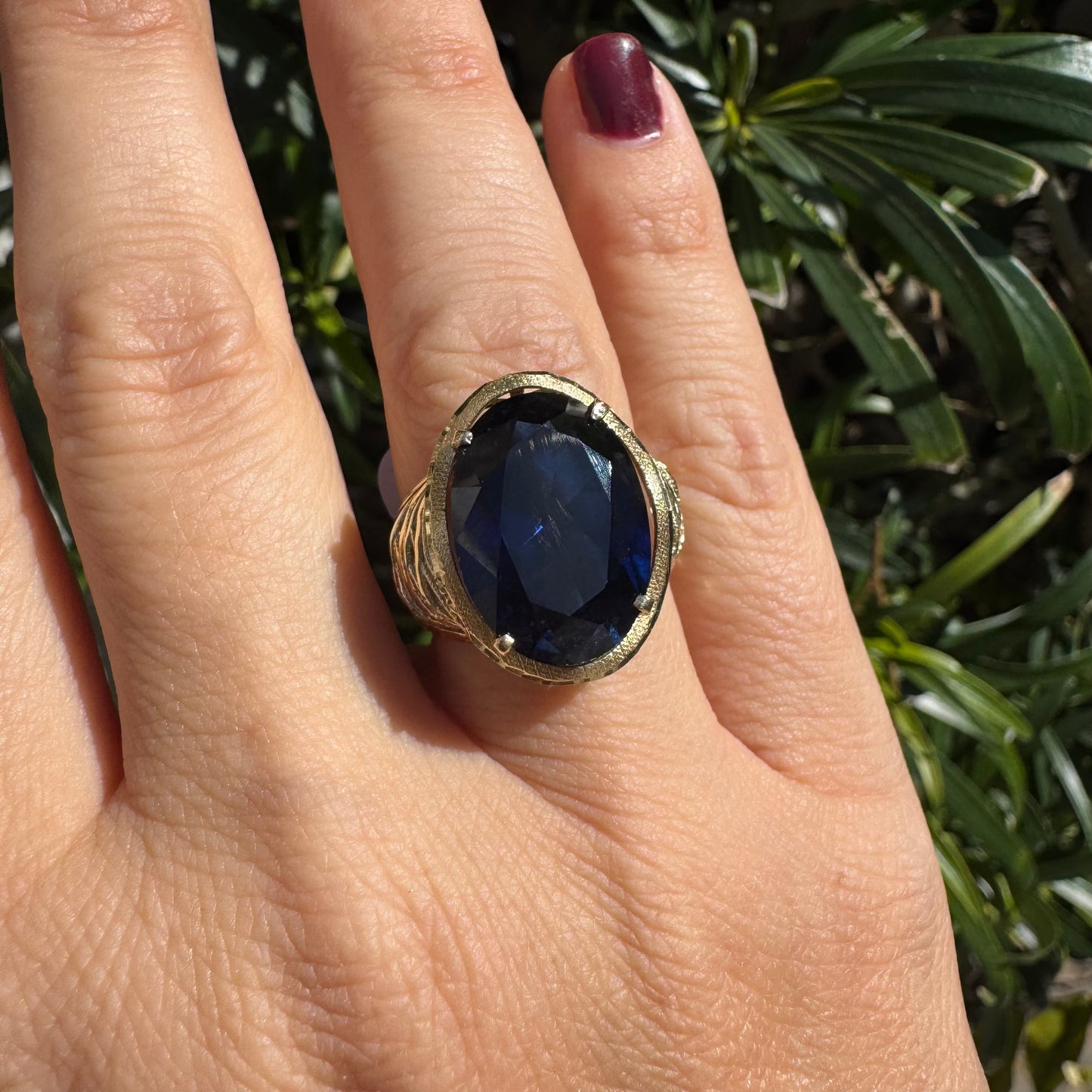 14K gold ring set with a deep navy-blue oval Sapphire in a dramatic openwork setting