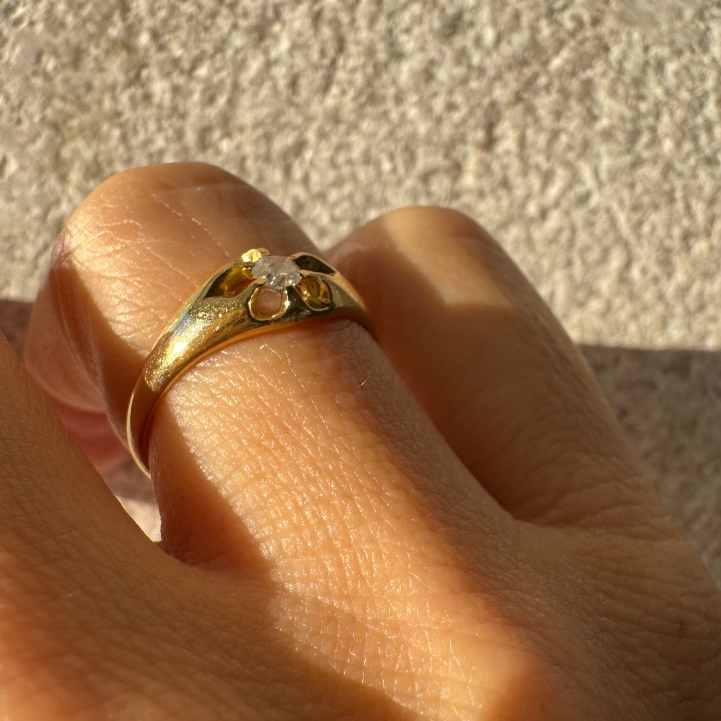 טבעת זהב צהוב 18 קראט בעיצוב פרח עדין, משובצת יהלום מרכזי בתוך עלי כותרת פתוחים.