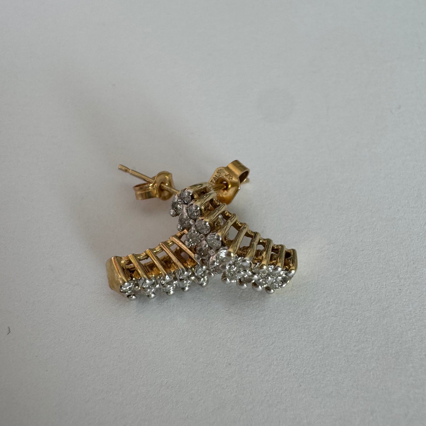 עגילי זהב צהוב 14 קראט בעיצוב חצי חישוק, משובצים יהלומים מנצנצים בשיבוץ צפוף המעניק מראה עשיר ונוכח.